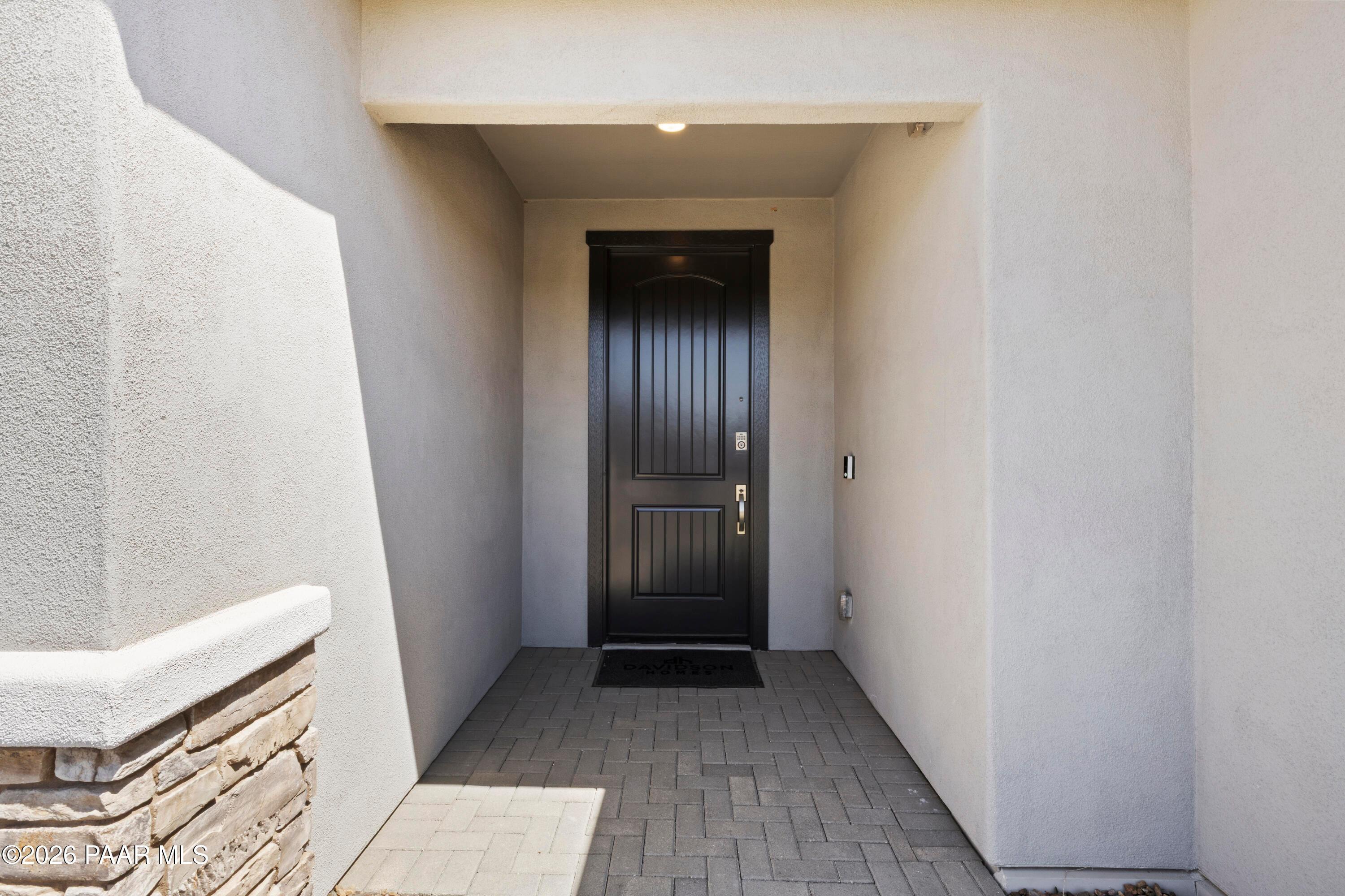 Elegant dark front door and stone-paved entryway of The Harmony A floor plan at Pronghorn Ranch, Prescott Valley, Arizona.
