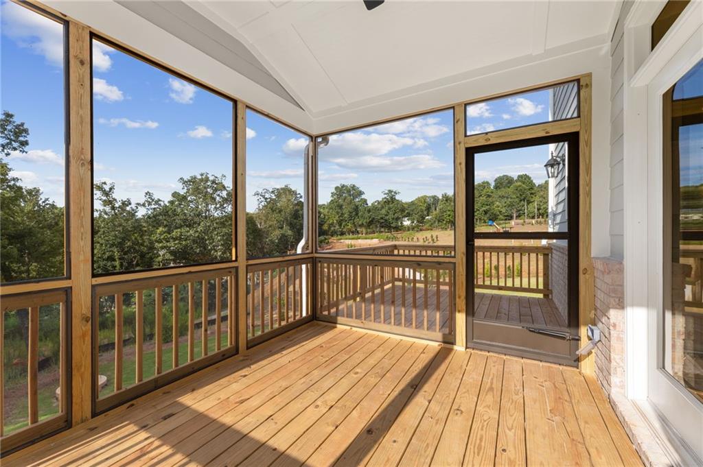 Screened porch with wooden deck, railing, ceiling fan overlooking wooded backyard in Davidson Homes The Hickory B, Buford, GA
