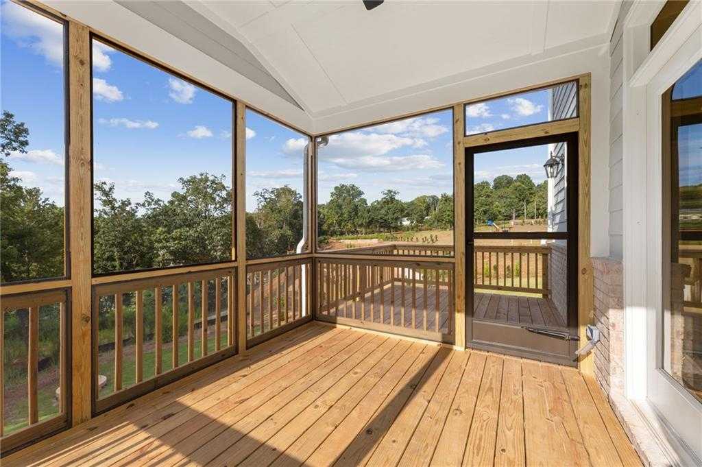 Screened porch with wooden deck, railing, ceiling fan overlooking wooded backyard in Davidson Homes The Hickory B, Buford, GA