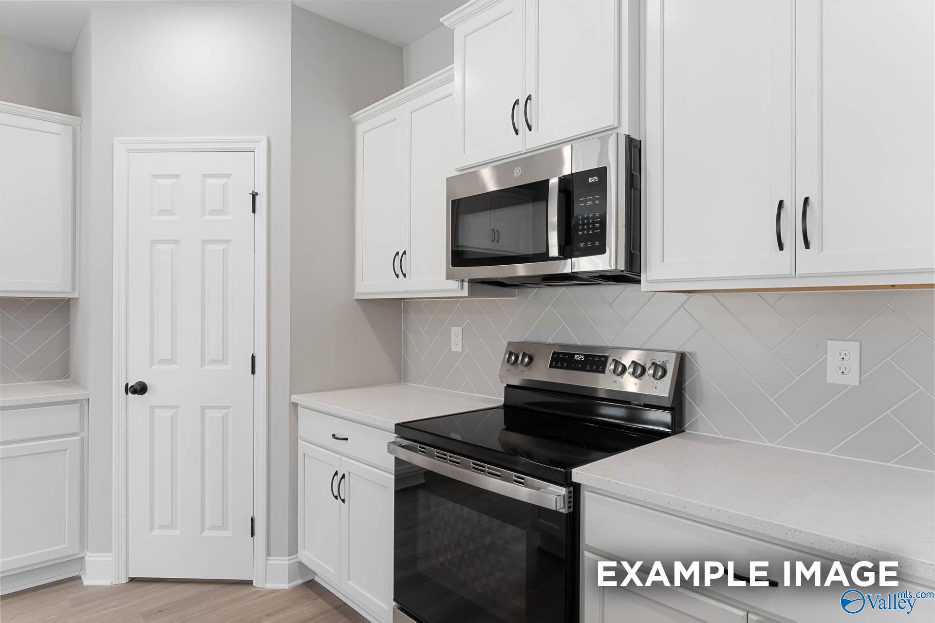 Modern kitchen featuring white shaker cabinets, stainless steel microwave and range, subway tile backsplash in Davidson Homes The Daphne D, Meridianville, AL