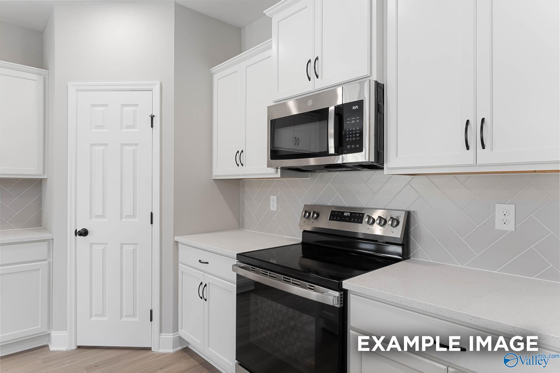 Modern kitchen featuring white shaker cabinets, stainless steel microwave and range, subway tile backsplash in Davidson Homes The Daphne D, Meridianville, AL