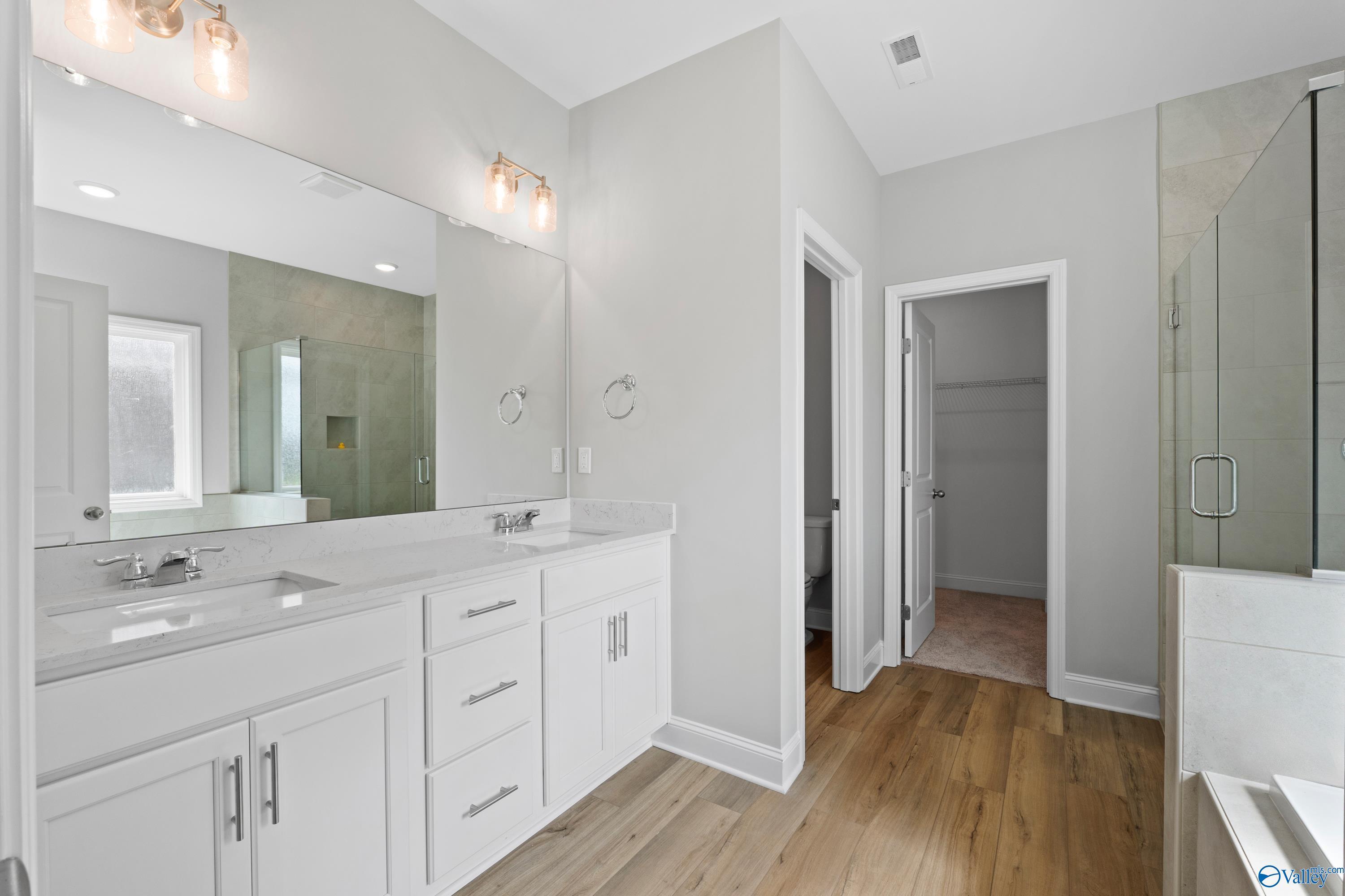 Elegant master bathroom with double white vanity, frameless glass shower, and gray walls in Davidson Homes The Everett B, Toney, Alabama