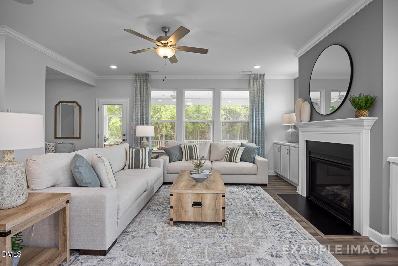 Cozy living room with beige sectional sofa, gas fireplace, large windows, ceiling fan in The Magnolia B 4-bedroom home by Davidson Homes, Angier, NC