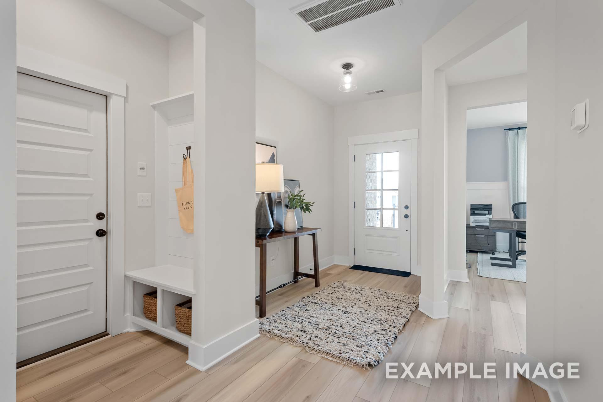 Spacious Ridgeport B entry foyer with white walls, light oak floors, wooden front door, coat bench, and console table