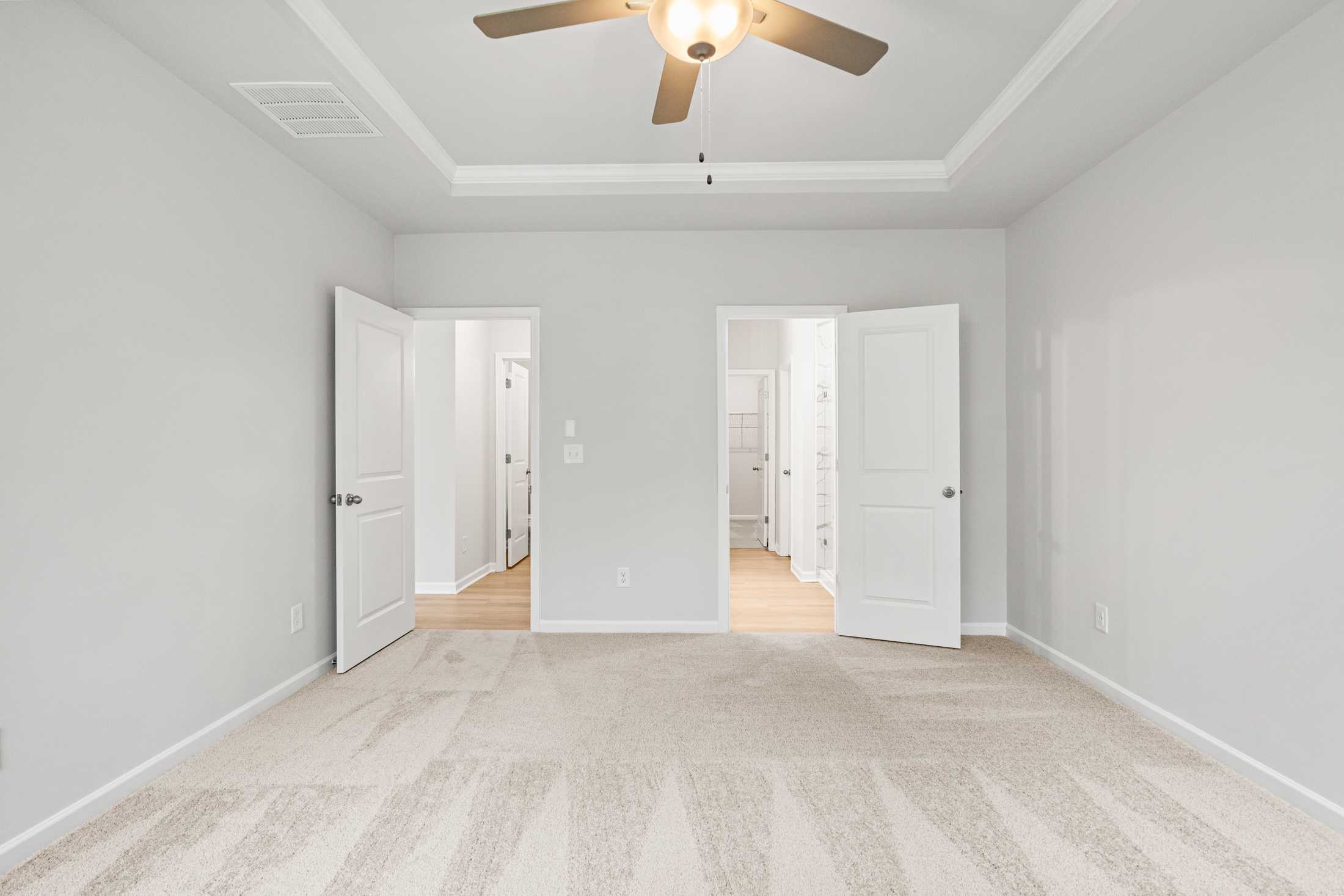 Spacious master suite in The Ash B at Wehunt Meadows with gray walls, ceiling fan, open bathroom and closet doors