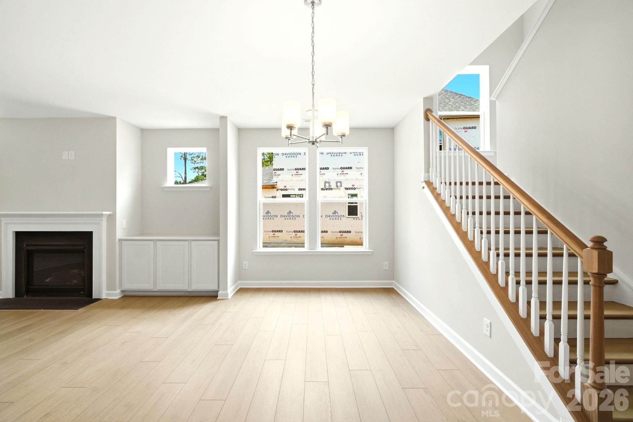 Light-filled living area with fireplace and staircase in The Magnolia B floor plan by Davidson Homes in Mooresville, NC.