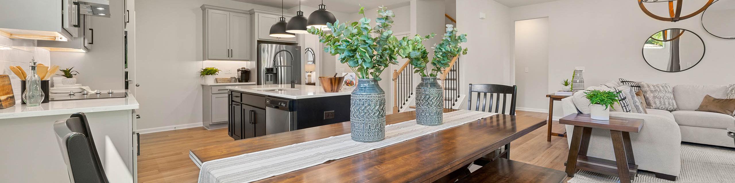 Open-concept kitchen dining area at Mountainbrook in Cartersville GA by Davidson Homes with white cabinets wooden table benches eucalyptus
