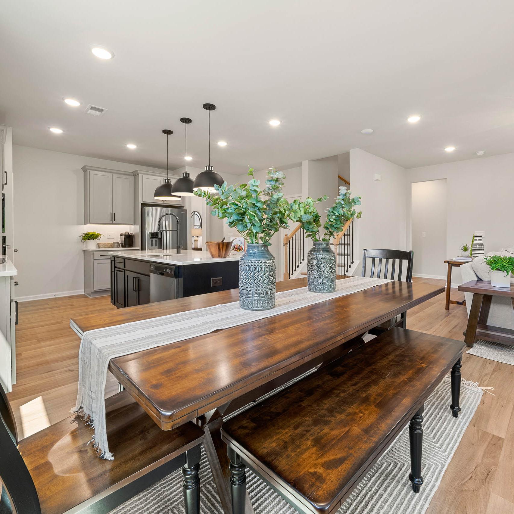 Open-concept kitchen dining area at Mountainbrook in Cartersville GA by Davidson Homes with white cabinets wooden table benches eucalyptus