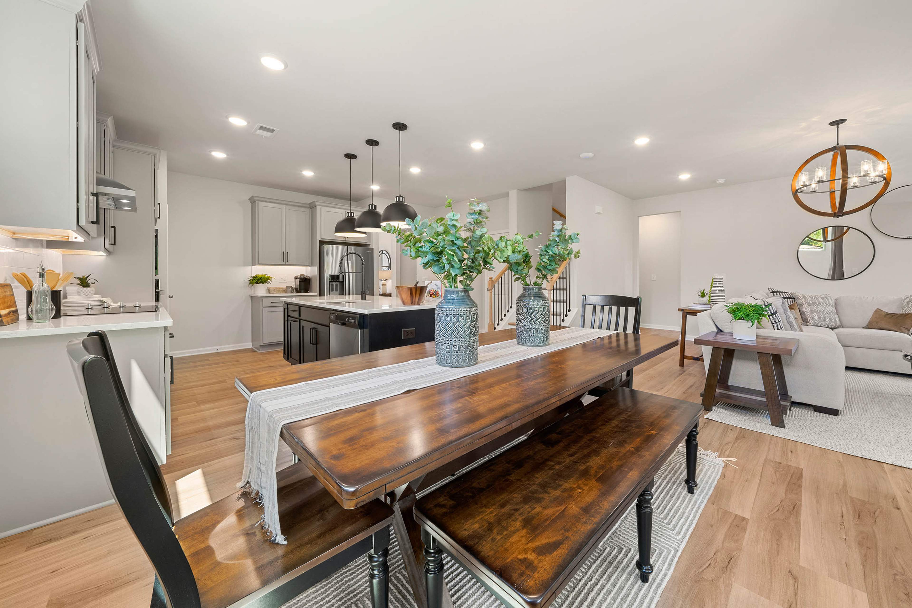 Open-concept kitchen dining area at Mountainbrook in Cartersville GA by Davidson Homes with white cabinets wooden table benches eucalyptus