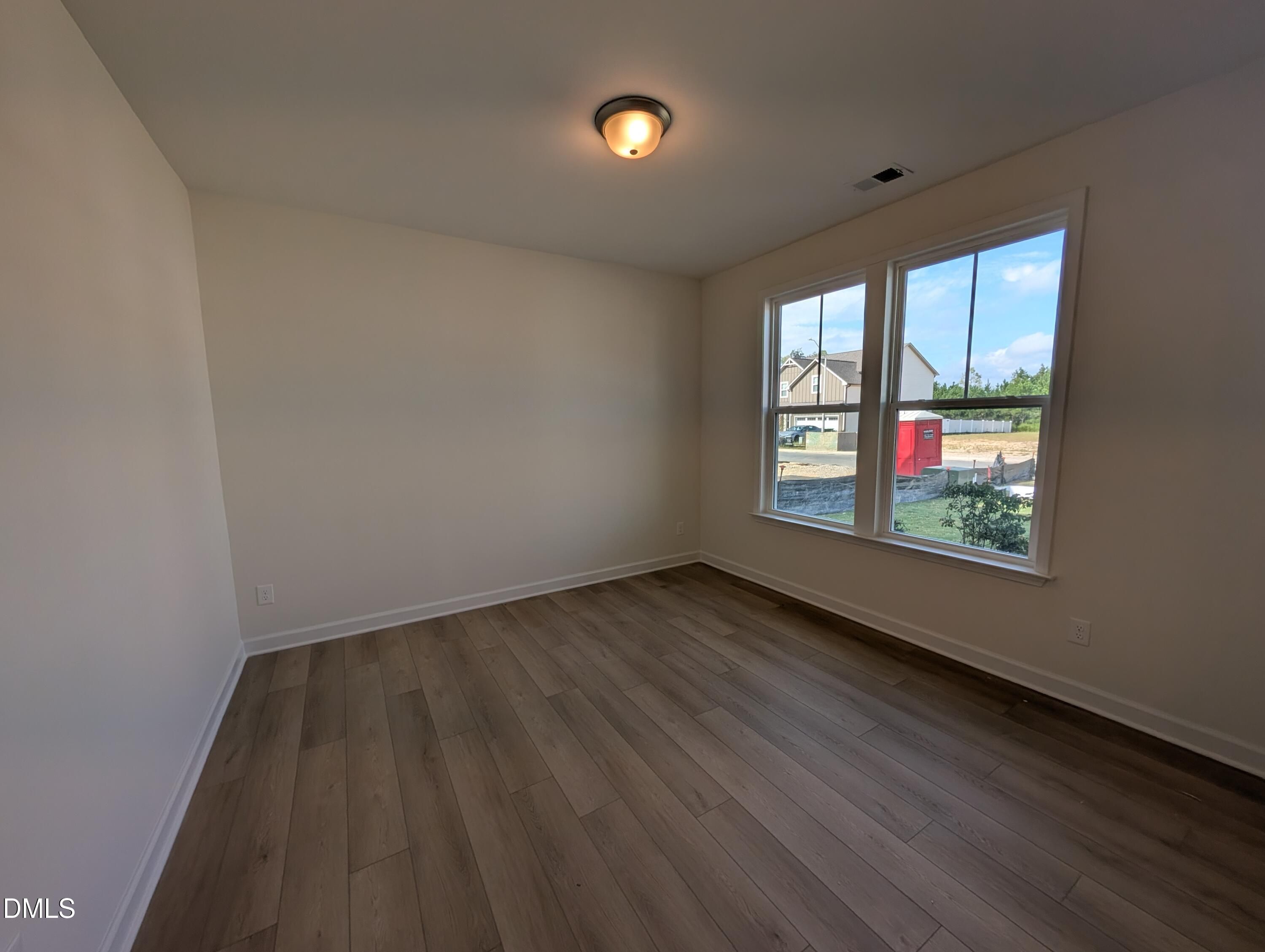 Bright empty bedroom with luxury vinyl plank flooring and double windows in Davidson Homes The Magnolia A, Wendell Ridge, NC