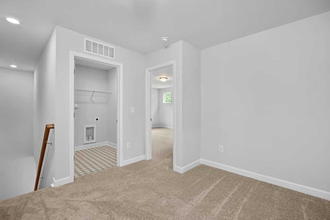 Upstairs laundry room with utility sink, white cabinets, and carpeted hallway access in Davidson Homes The Durham C, Wylie, Texas