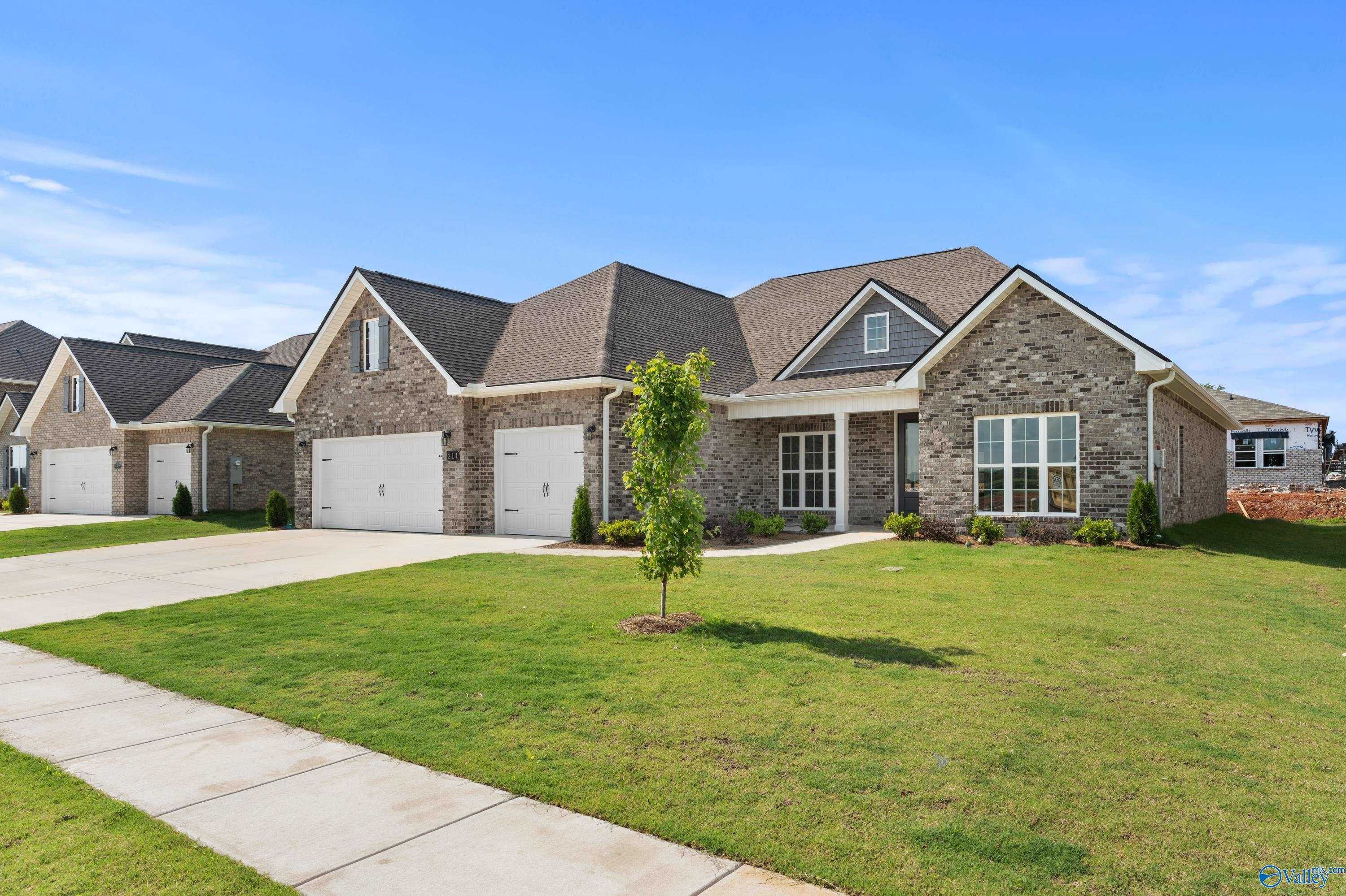 The Finleigh single-story brick home with 3-car garage, driveway, and lush green lawn in Kendall Farms, Toney, Alabama
