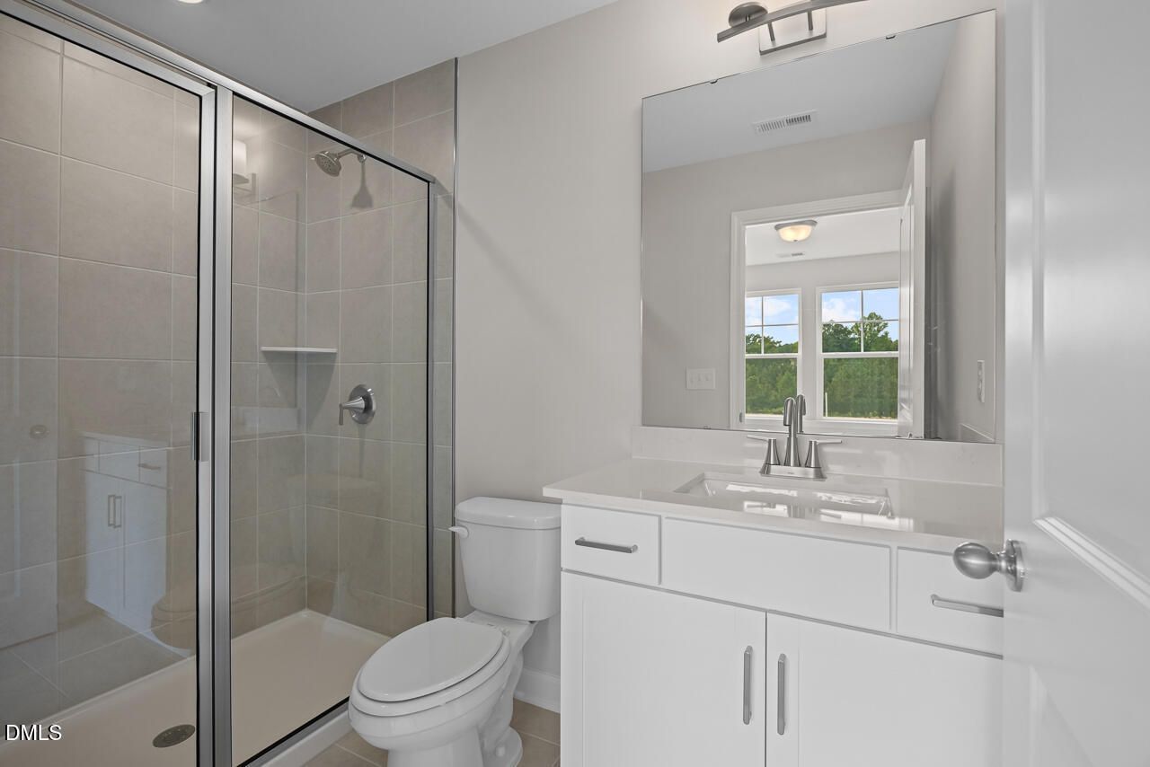 Modern bathroom with glass-enclosed shower and white vanity in The Chestnut floor plan at Wendell Ridge, Wendell, NC.