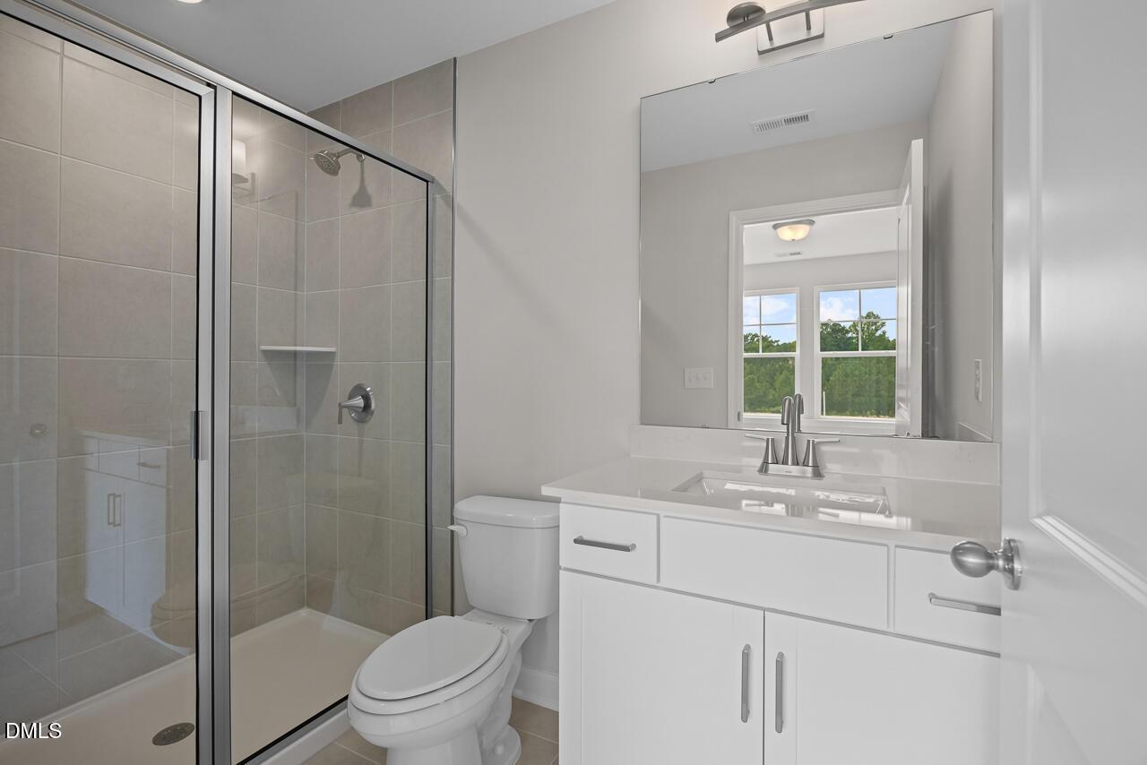 Modern bathroom with glass-enclosed shower and white vanity in The Chestnut floor plan at Wendell Ridge, Wendell, NC.