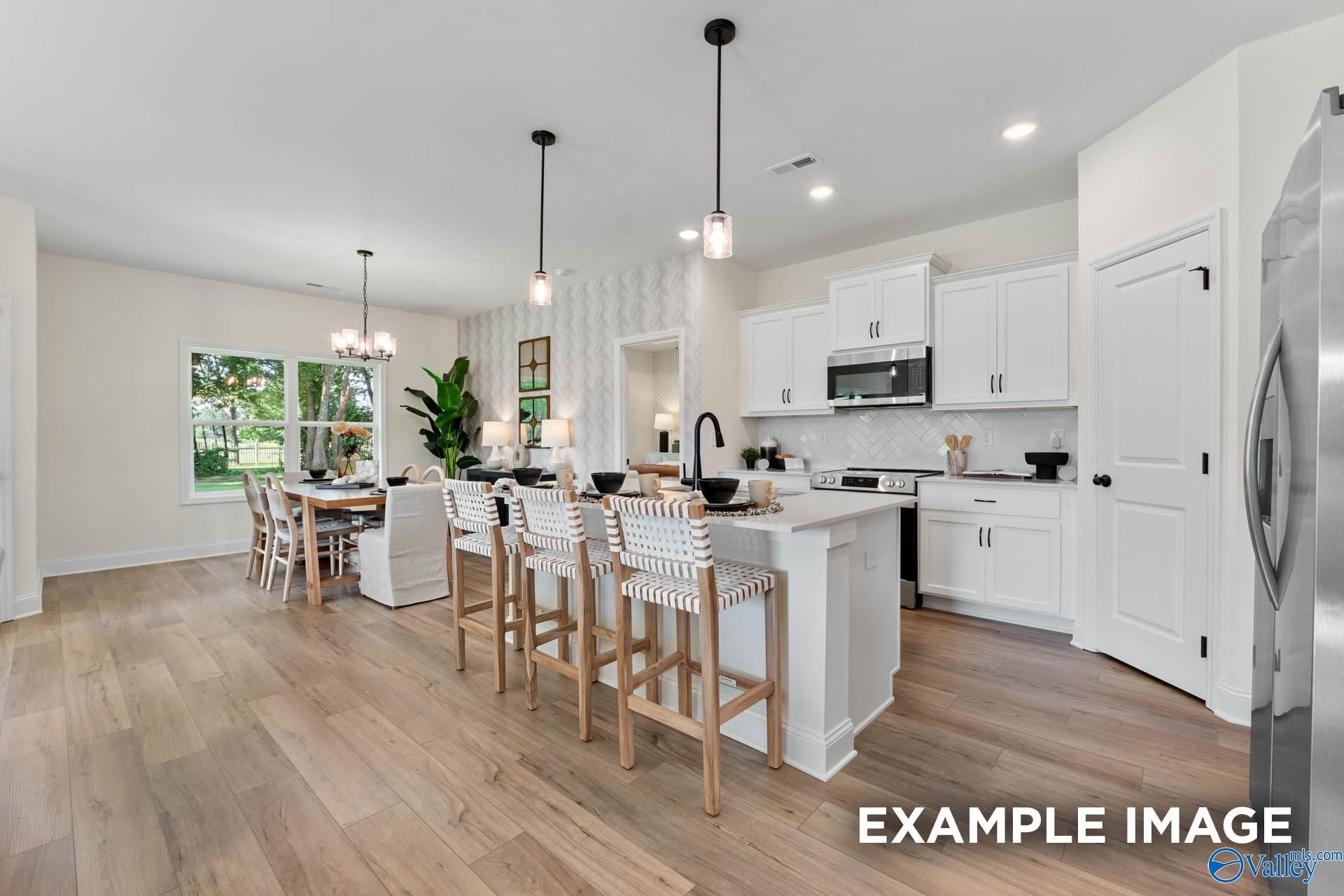 Bright open-concept kitchen with white cabinets, large island bar, stainless appliances, and dining area in Davidson Homes The Franklin, Huntsville