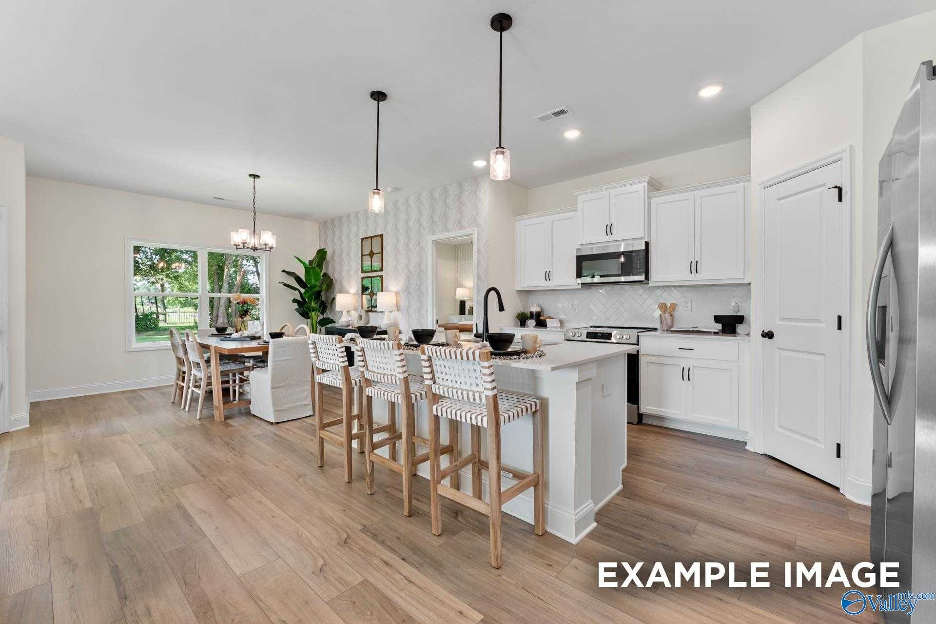 Bright open-concept kitchen with white cabinets, large island bar, stainless appliances, and dining area in Davidson Homes The Franklin, Huntsville