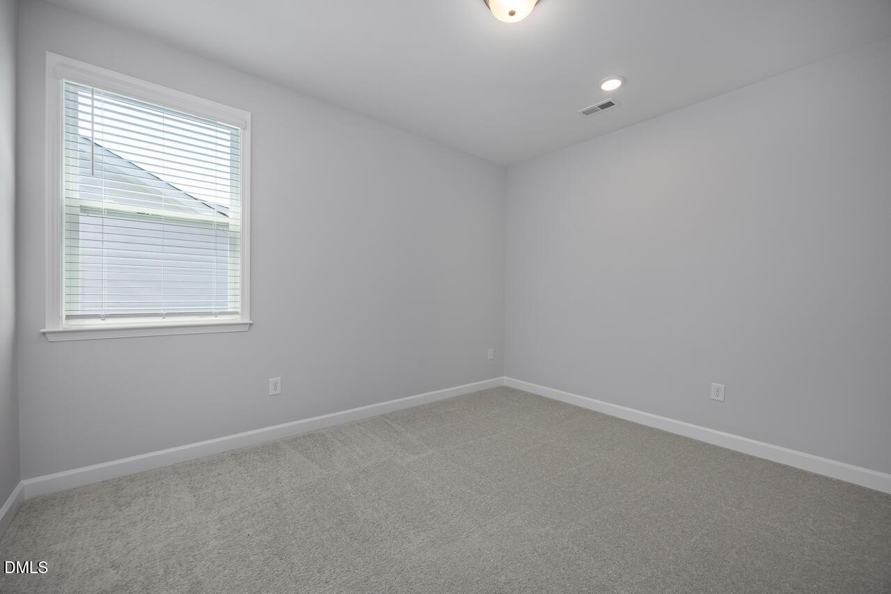Bright, neutral bedroom with plush carpeting in The Ashport L floor plan at Sage on North Main, Wake Forest, NC.