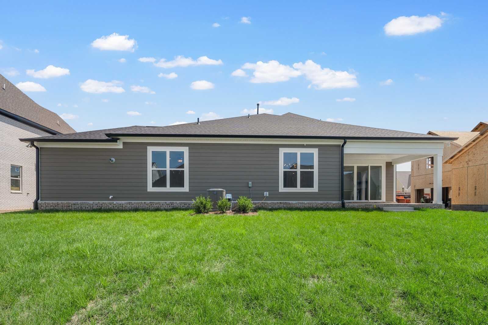 Rear view of The Hathaway two-story home with covered patio, large windows, and lush green lawn in Shelton Square, Murfreesboro, TN