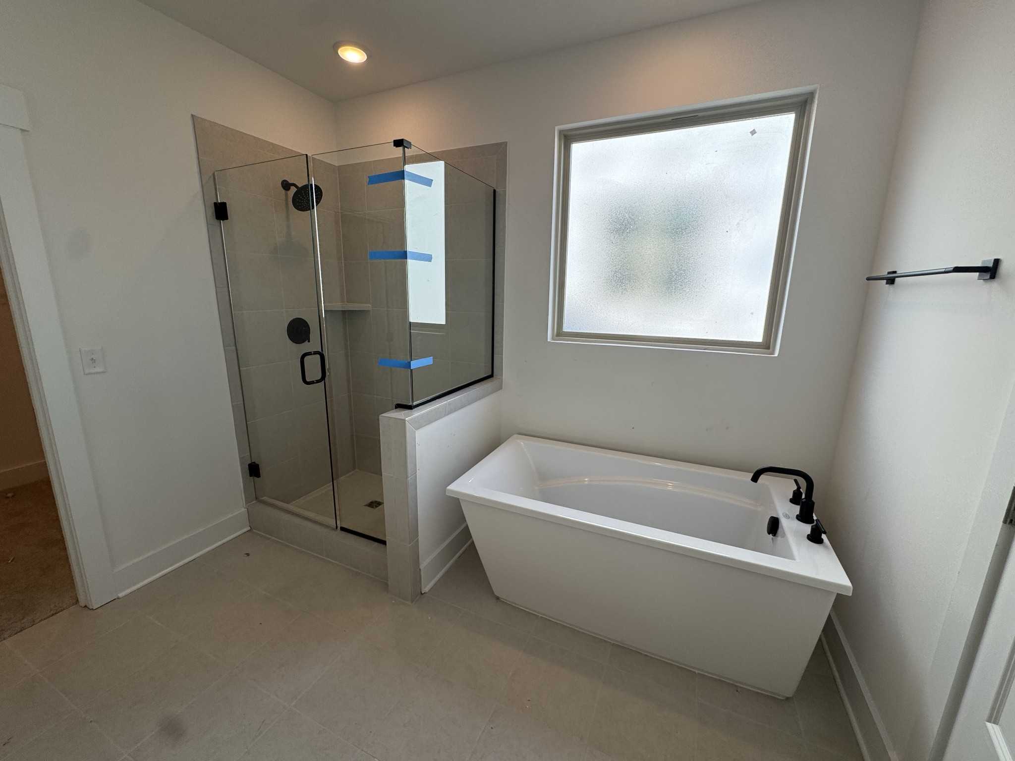 Elegant master bathroom with glass walk-in shower, freestanding tub, and frosted window in Davidson Homes The Ridgeport, Gallatin, TN