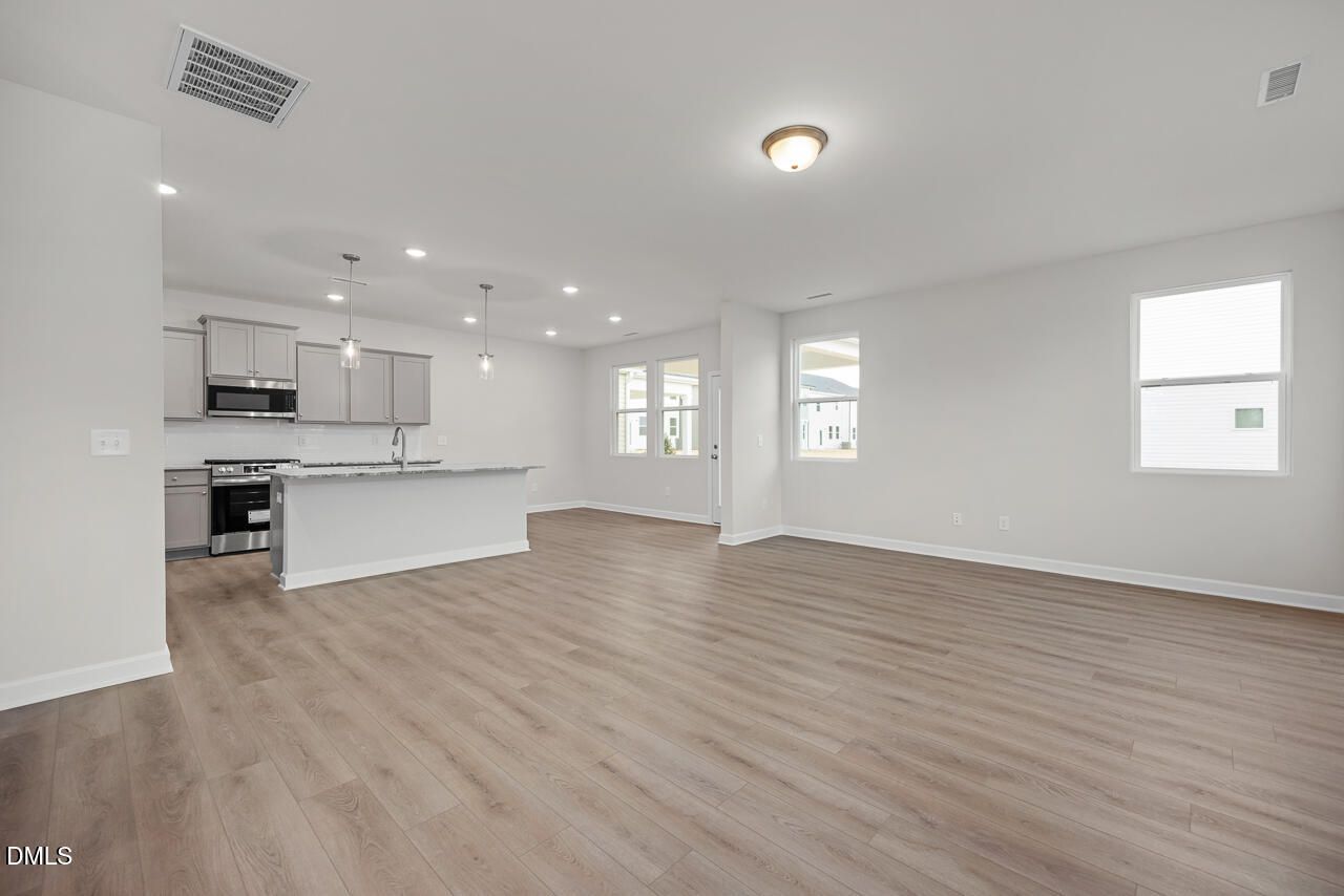 Open-concept kitchen with white shaker cabinets, stainless steel appliances, and oversized island in Davidson Homes The Gavin B, Lillington, NC