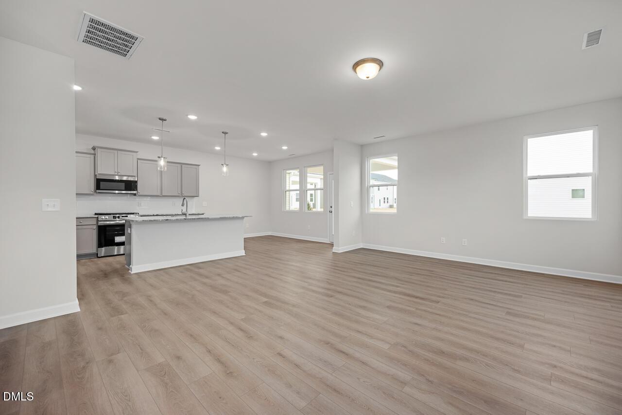 Open-concept kitchen with white shaker cabinets, stainless steel appliances, and oversized island in Davidson Homes The Gavin B, Lillington, NC