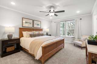 Spacious master bedroom in The Washington H townhome with wooden king bed, neutral bedding, and large window views