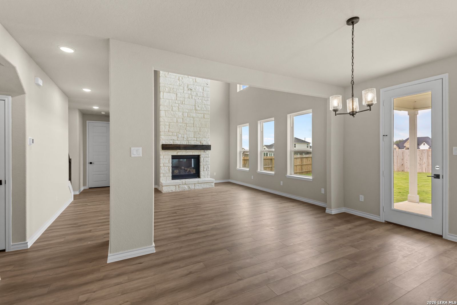 Spacious living room with stone fireplace in The Danbury H floor plan at The Reserve at Potranco Oaks, Castroville, Texas.