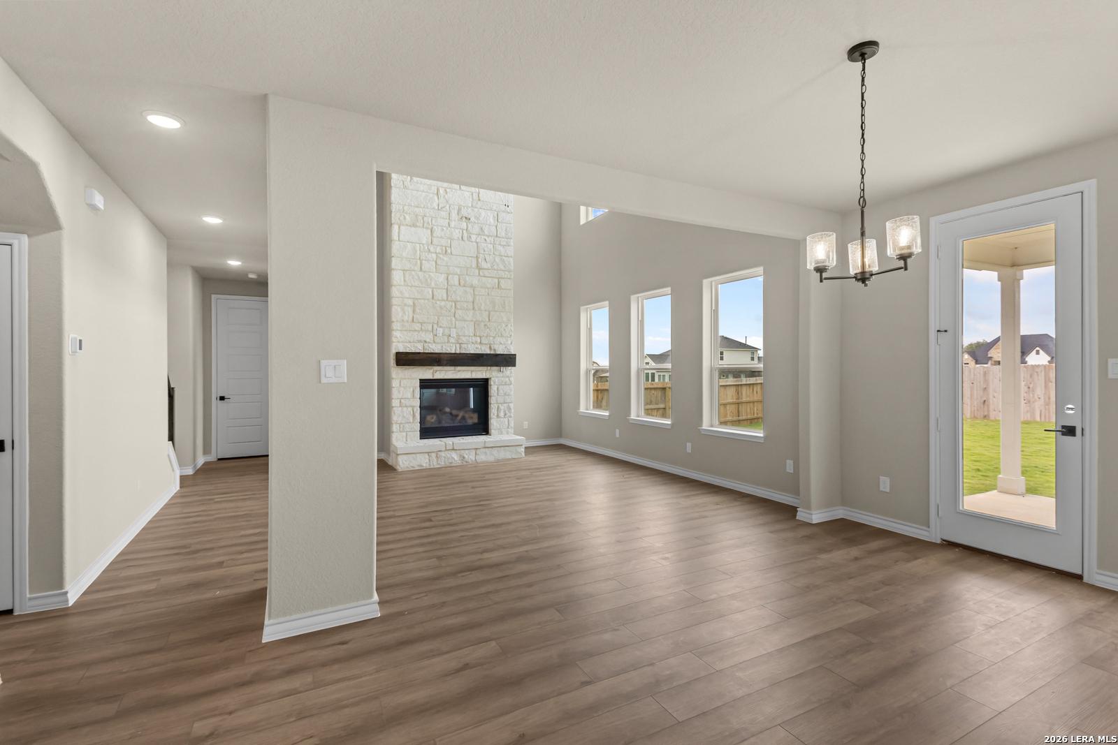 Spacious living room with stone fireplace in The Danbury H floor plan at The Reserve at Potranco Oaks, Castroville, Texas.