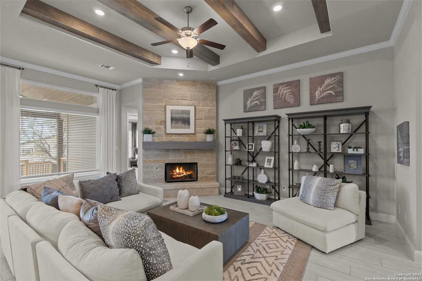 Cozy living room with stone fireplace, wooden beam ceiling, plush sectional sofa in Davidson Homes The Garner B, Castroville, Texas