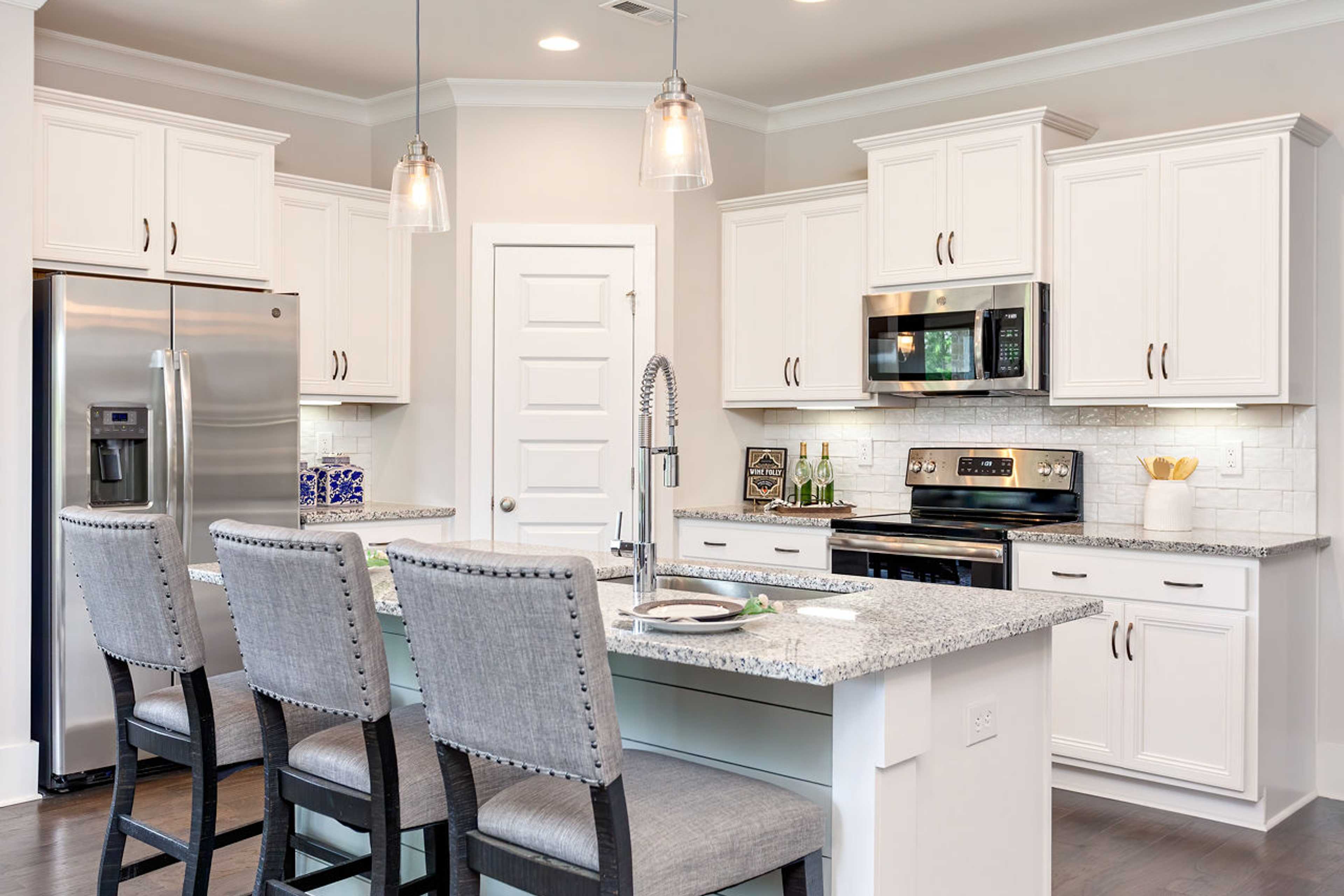 Spacious kitchen in Williams Pointe, Huntsville AL with white shaker cabinets, granite island, stainless steel appliances and bar seating