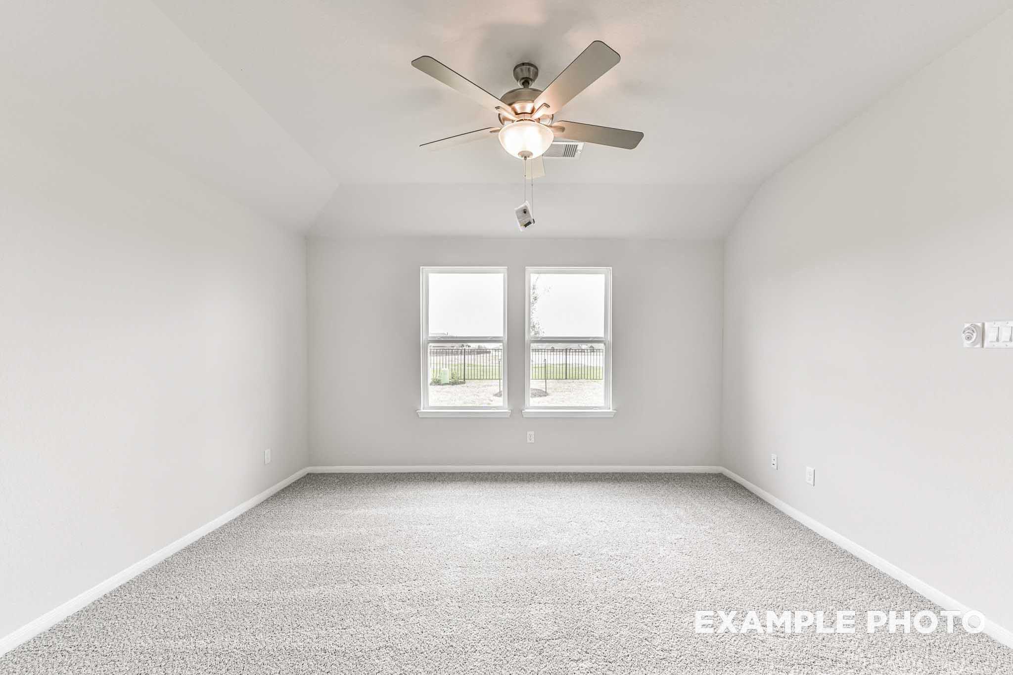 Spacious master bedroom in The Laguna A home with white walls, large windows, ceiling fan, and carpet flooring in Rosharon, TX