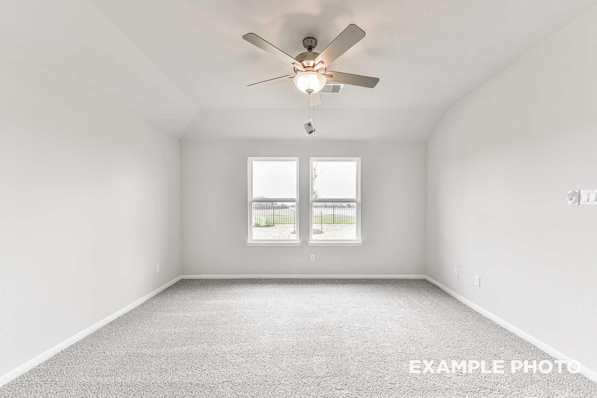 Spacious master bedroom in The Laguna A home with white walls, large windows, ceiling fan, and carpet flooring in Rosharon, TX