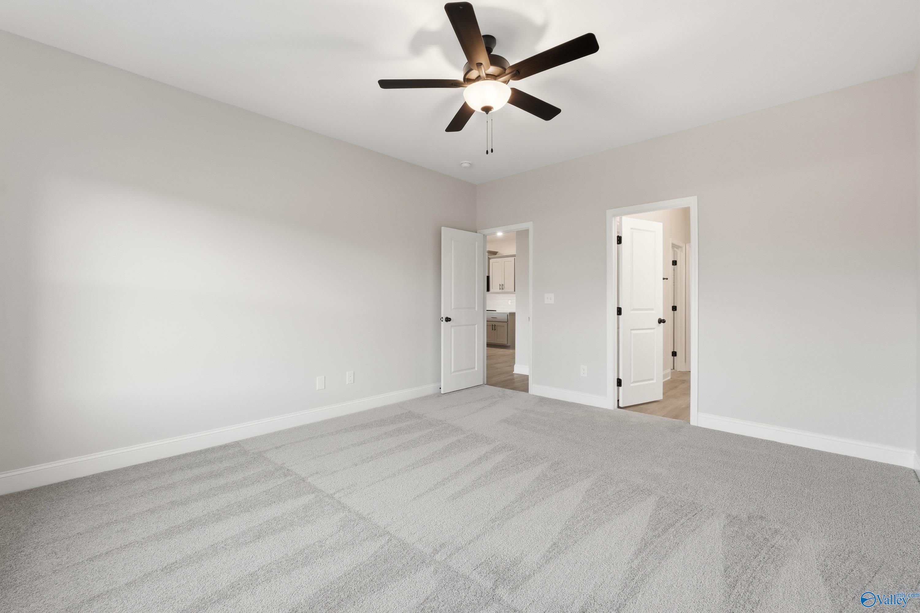 Spacious secondary bedroom featuring ceiling fan, gray carpet, and en-suite bathroom in Davidson Homes The Daphne C, Athens, Alabama