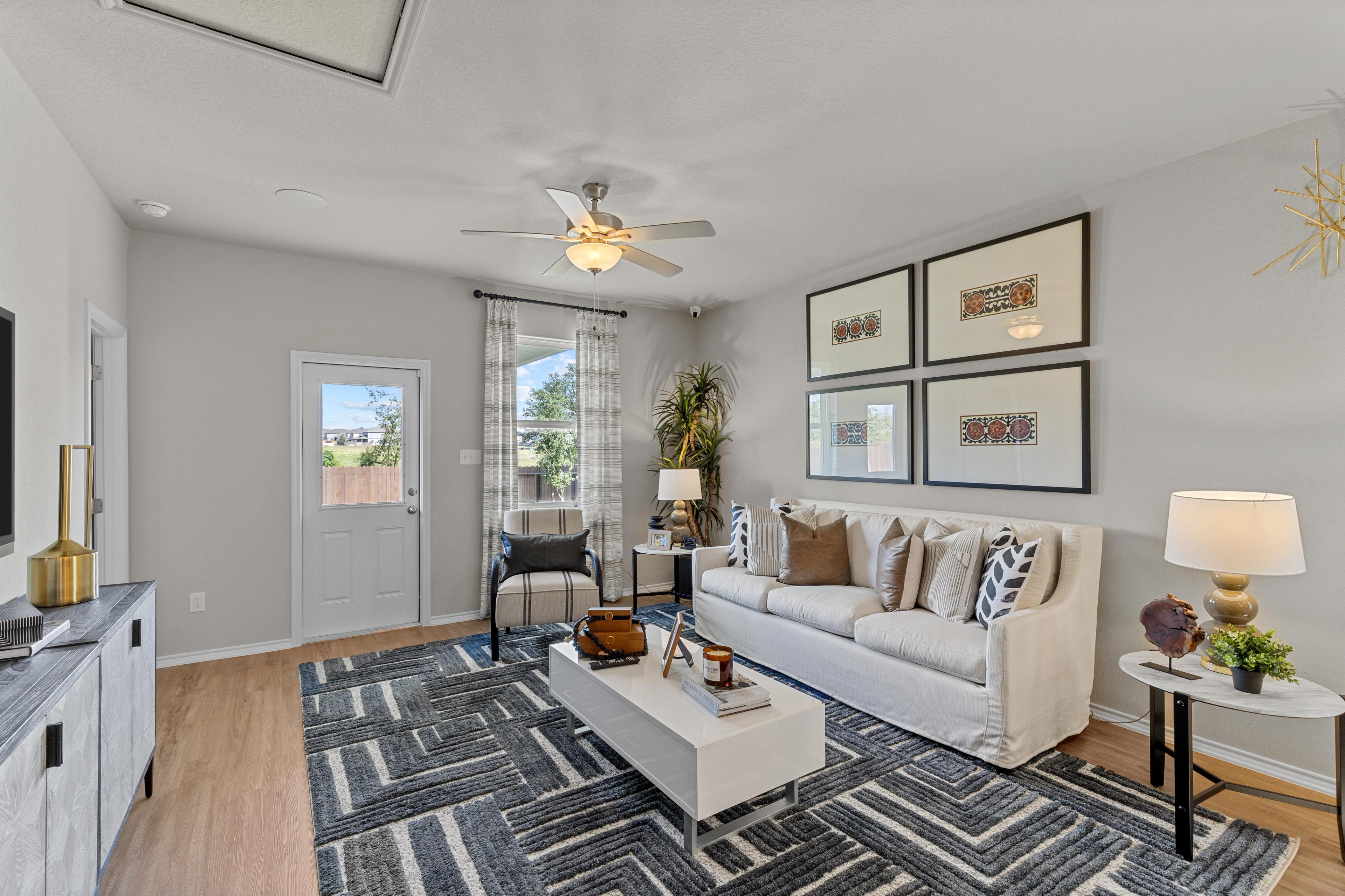 Spacious living room in The Sabine B by Davidson Homes featuring white sofa, geometric rug, artwork, and sliding doors to patio