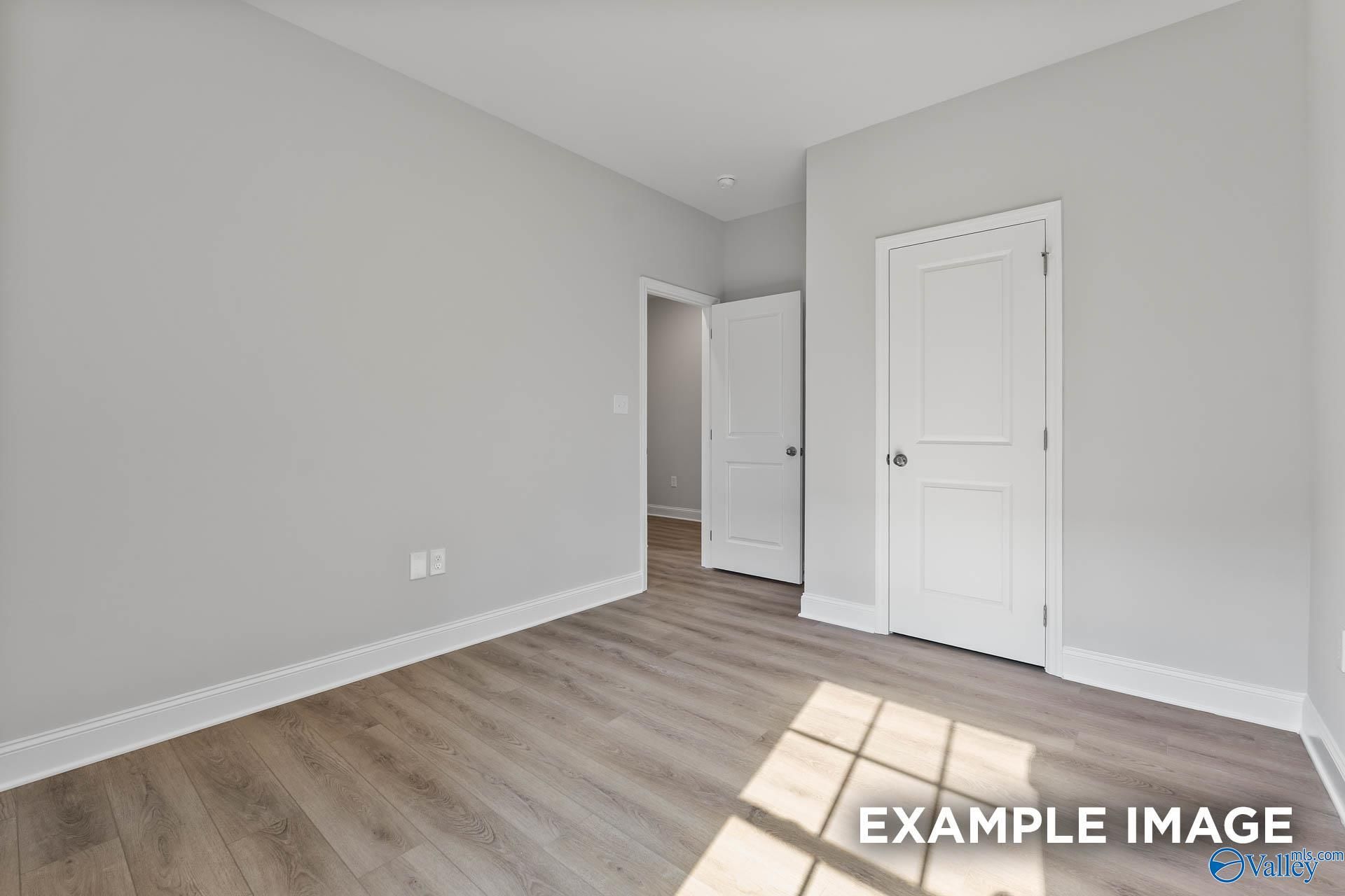 Bright secondary bedroom with light gray walls, white doors, and luxury vinyl plank floors in The Asheville V, Davidson Homes, Athens, AL
