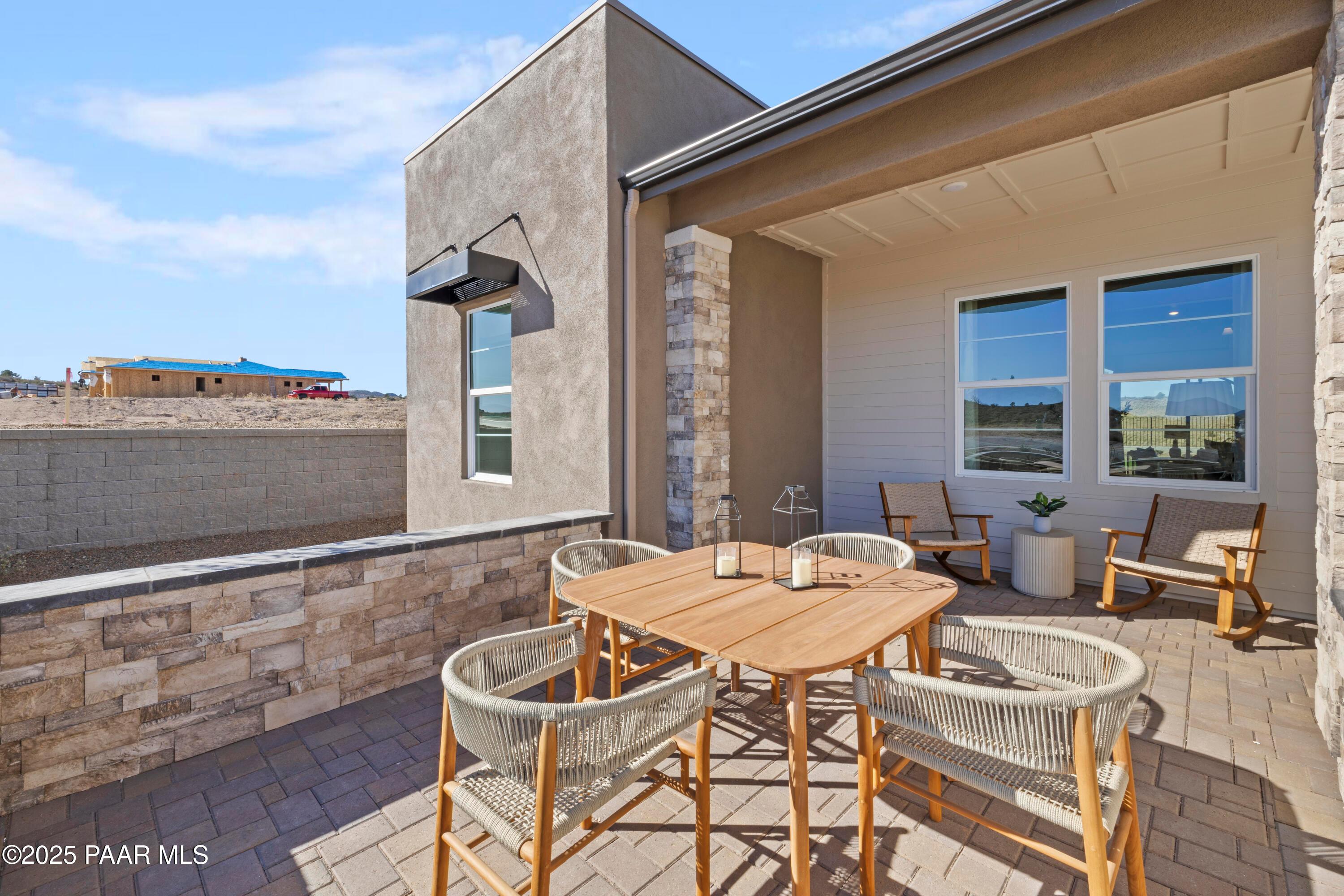 Inviting covered patio with teak dining table, rattan chairs, and lanterns in Davidson Homes The Blaze D, Hidden Hills, Prescott AZ