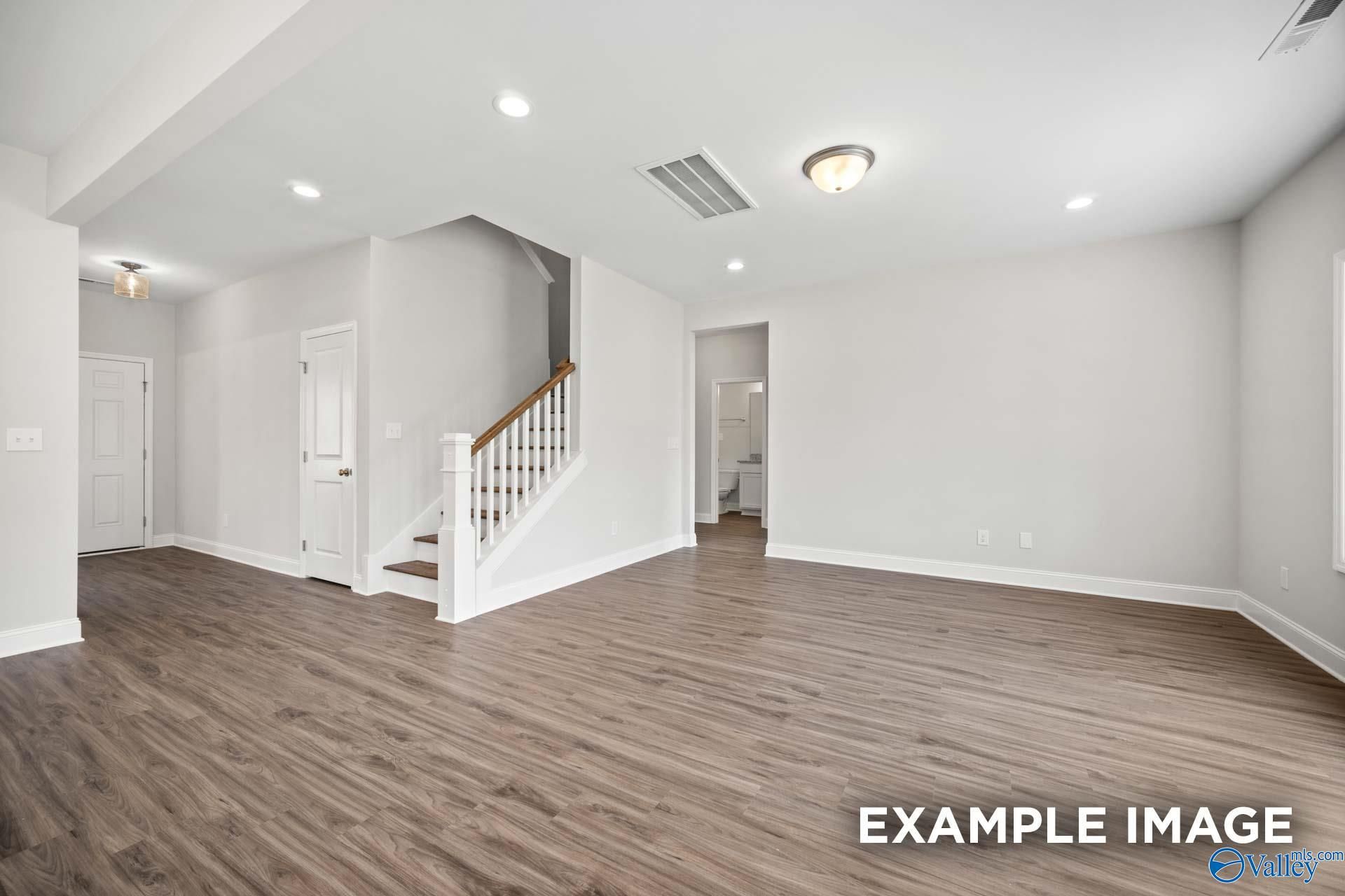 Open-concept living area with staircase and wood-style flooring in The Shelby B floor plan, Jaguar Hills, Huntsville.