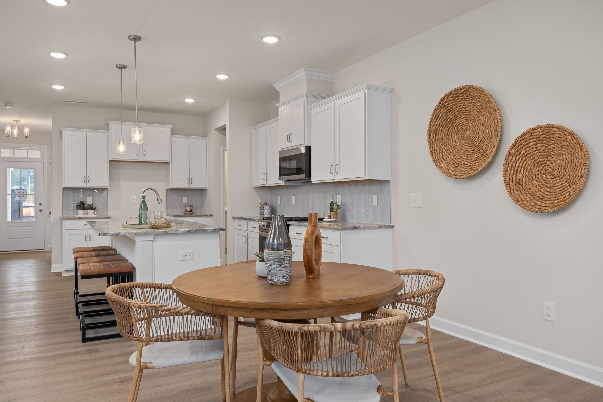 Modern kitchen and dining area at Gregory Village in Lillington, NC, featuring white cabinetry, island, and wood decor.