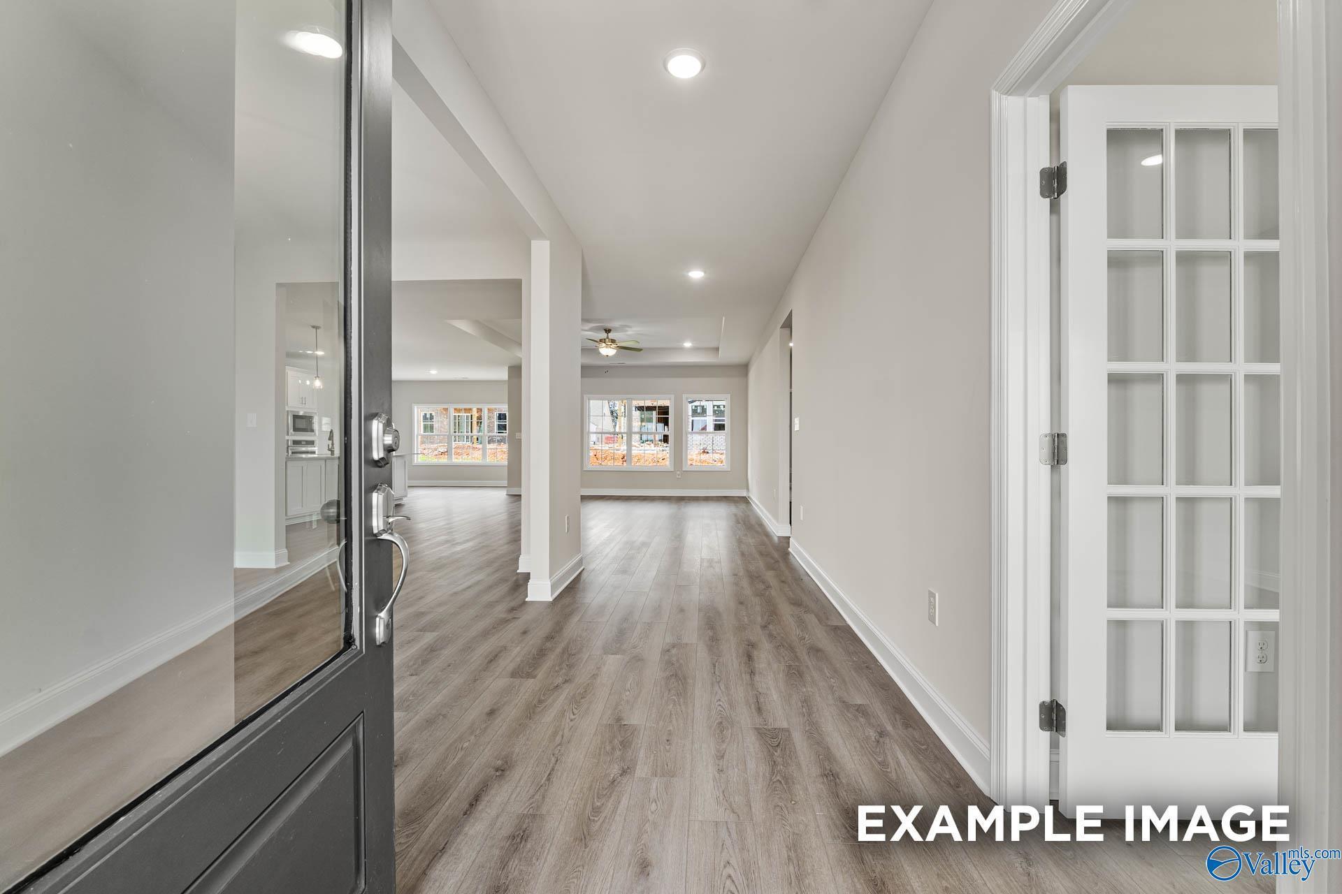 Spacious entry hallway with open glass front door, luxury vinyl plank floors, and arched openings in Davidson Homes The Finleigh, Huntsville AL