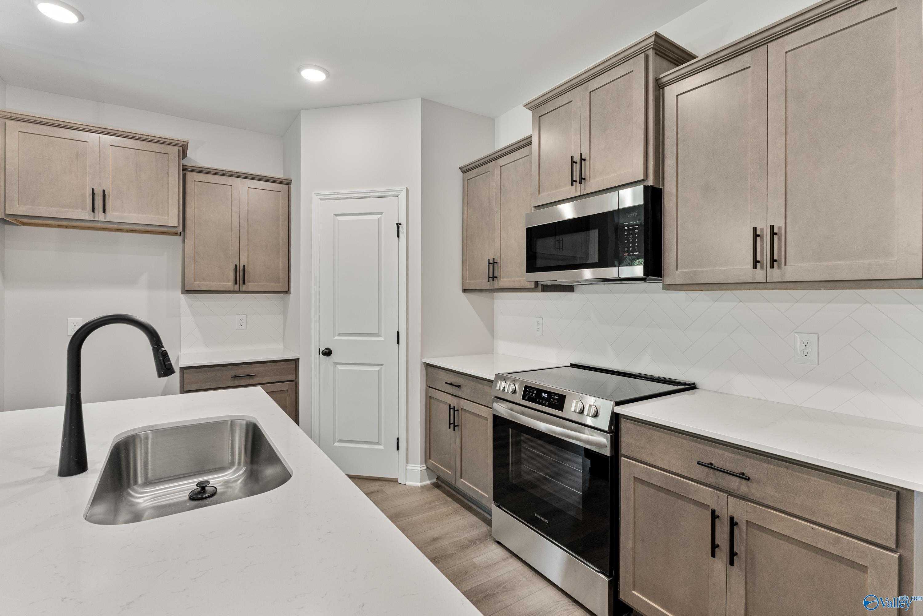 Modern kitchen with white quartz island, stainless steel appliances, shaker cabinets in The Daphne 4-bedroom home, Huntsville AL