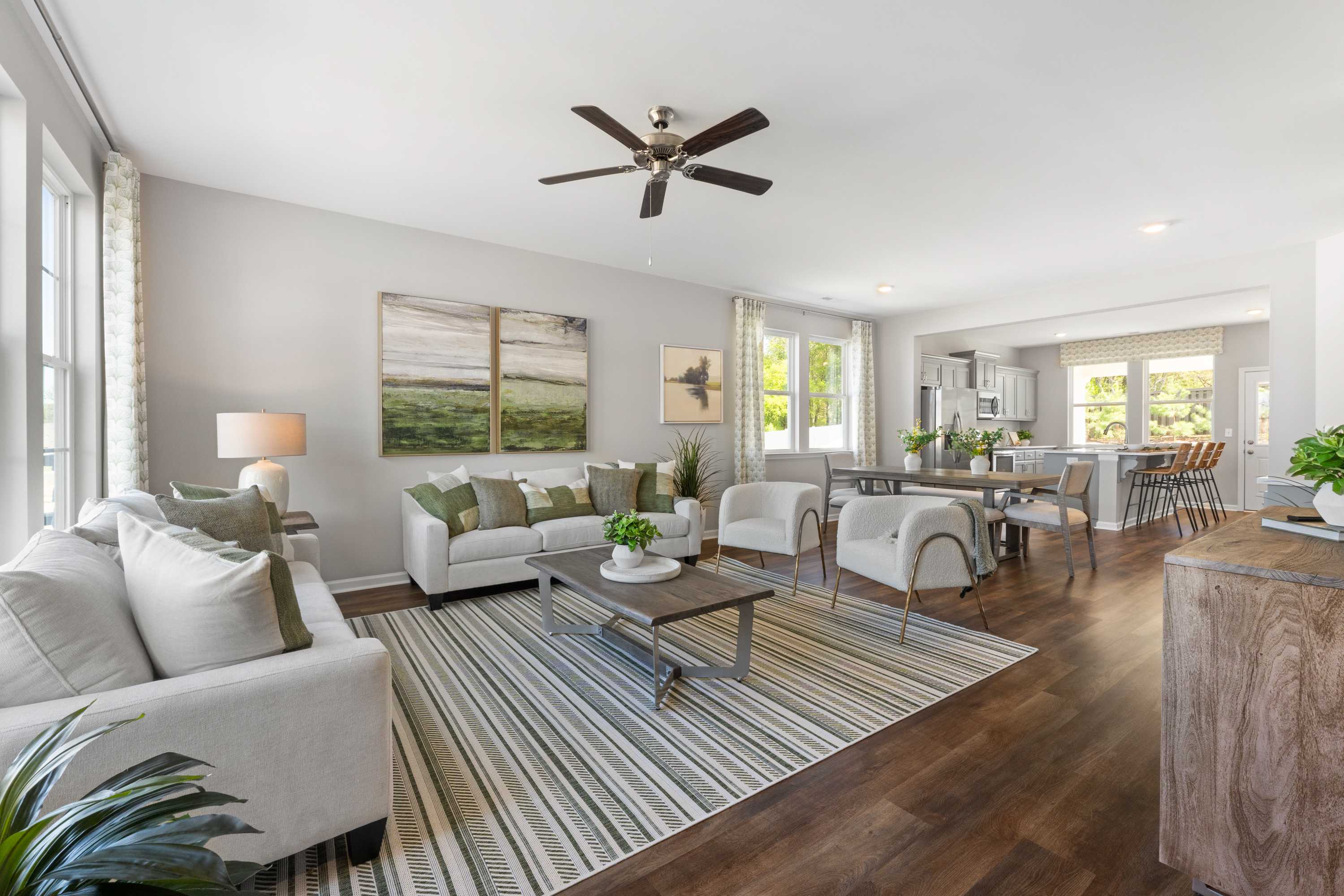 Open-concept living room at Evergreen Mill in Madison AL with neutral tones, hardwood floors, ceiling fan, and adjacent dining area