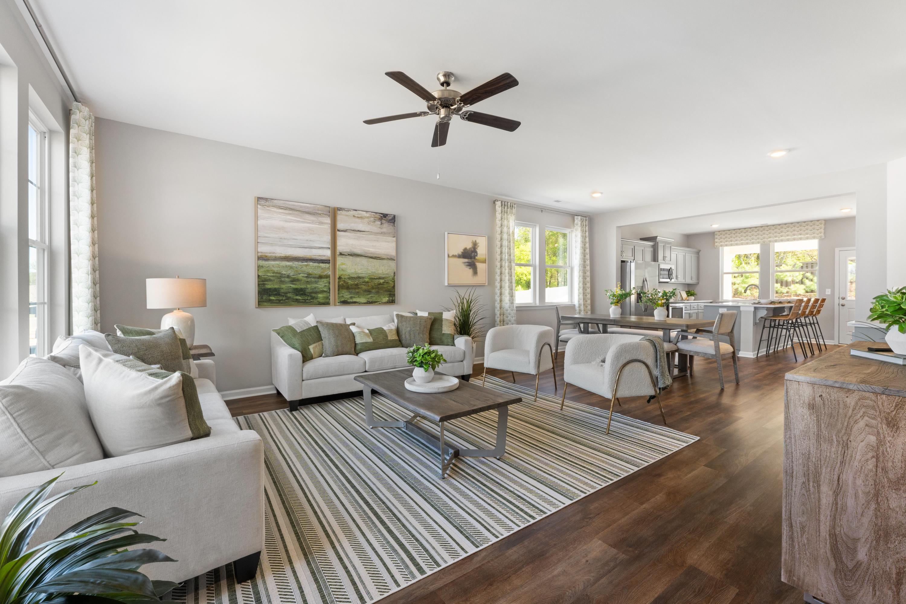 Open-concept living room at Evergreen Mill in Madison AL with neutral tones, hardwood floors, ceiling fan, and adjacent dining area