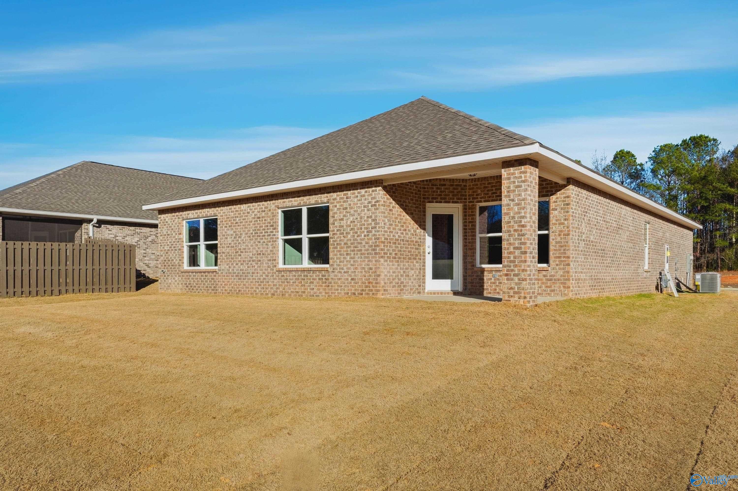 Single-story brick home with gabled shingle roof, large windows, and side door in grassy yard, The Highlands, Arab, Alabama - Davidson Homes Daphne C