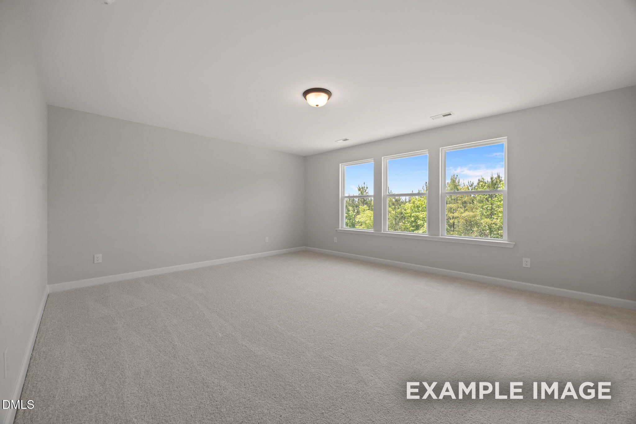 Bright spacious bedroom with neutral carpet and large windows overlooking trees in Davidson Homes The Beech, Wendell, NC