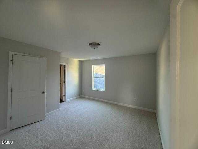 Bright secondary bedroom with large window, neutral gray walls, and carpeted floor in Davidson Homes The Gavin B, Lillington, NC