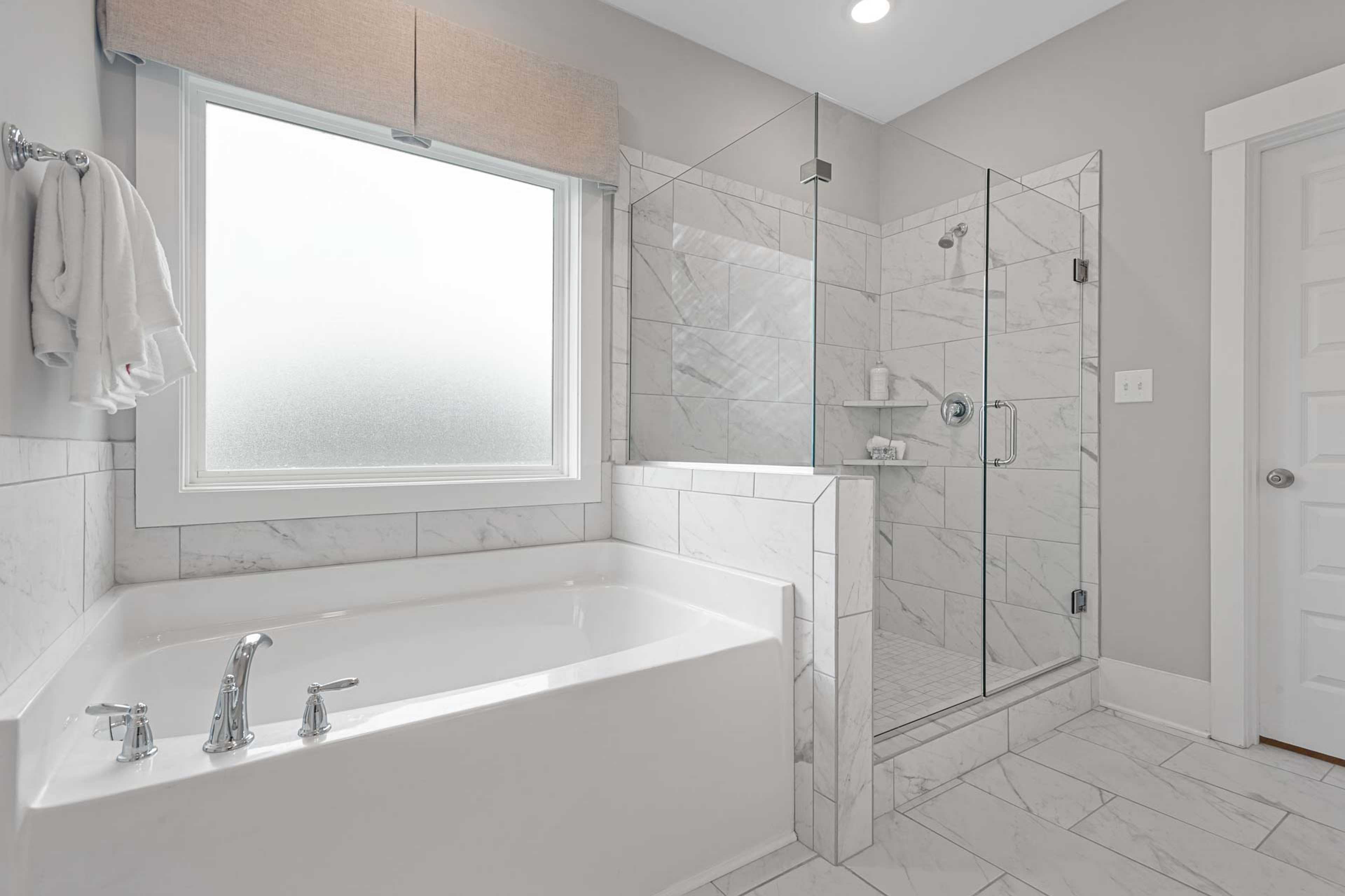 Spacious master bathroom at Monteagle Cove in Owens Cross Roads Alabama with freestanding tub, glass shower, and marble tiles