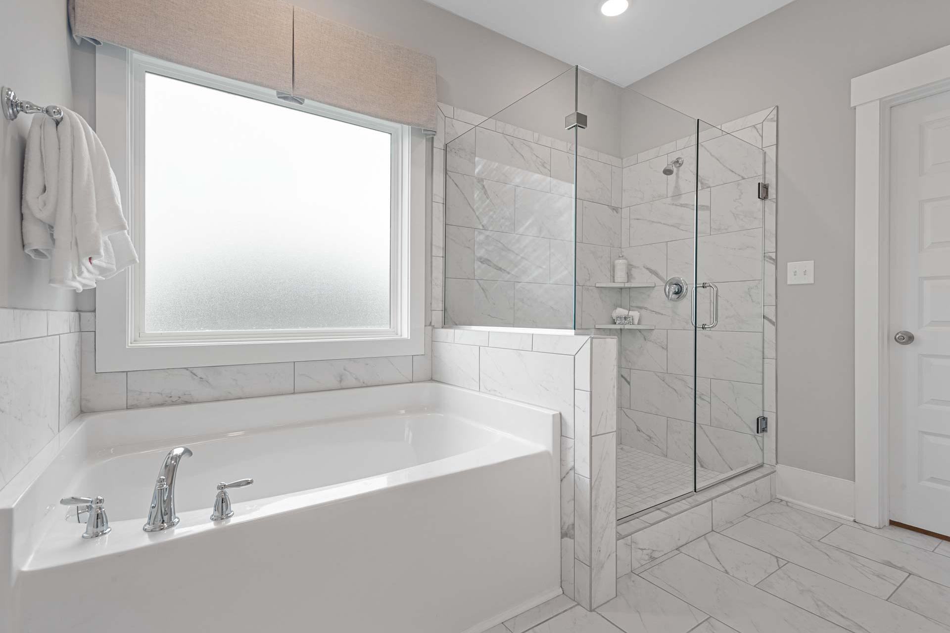 Spacious master bathroom at Monteagle Cove in Owens Cross Roads Alabama with freestanding tub, glass shower, and marble tiles