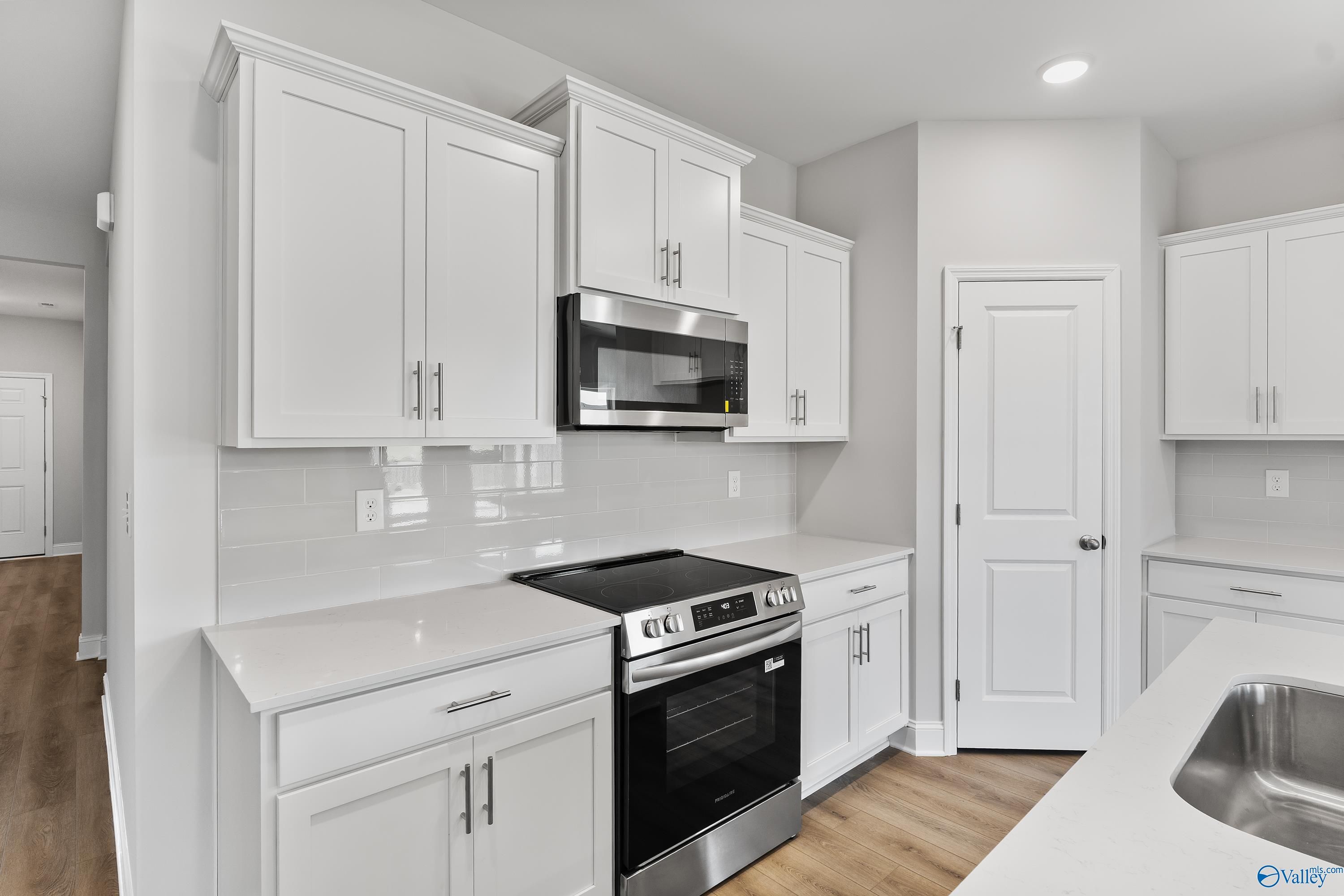 Modern white kitchen with stainless steel appliances, subway tile backsplash in Davidson Homes The Daphne, Hazel Green, Alabama