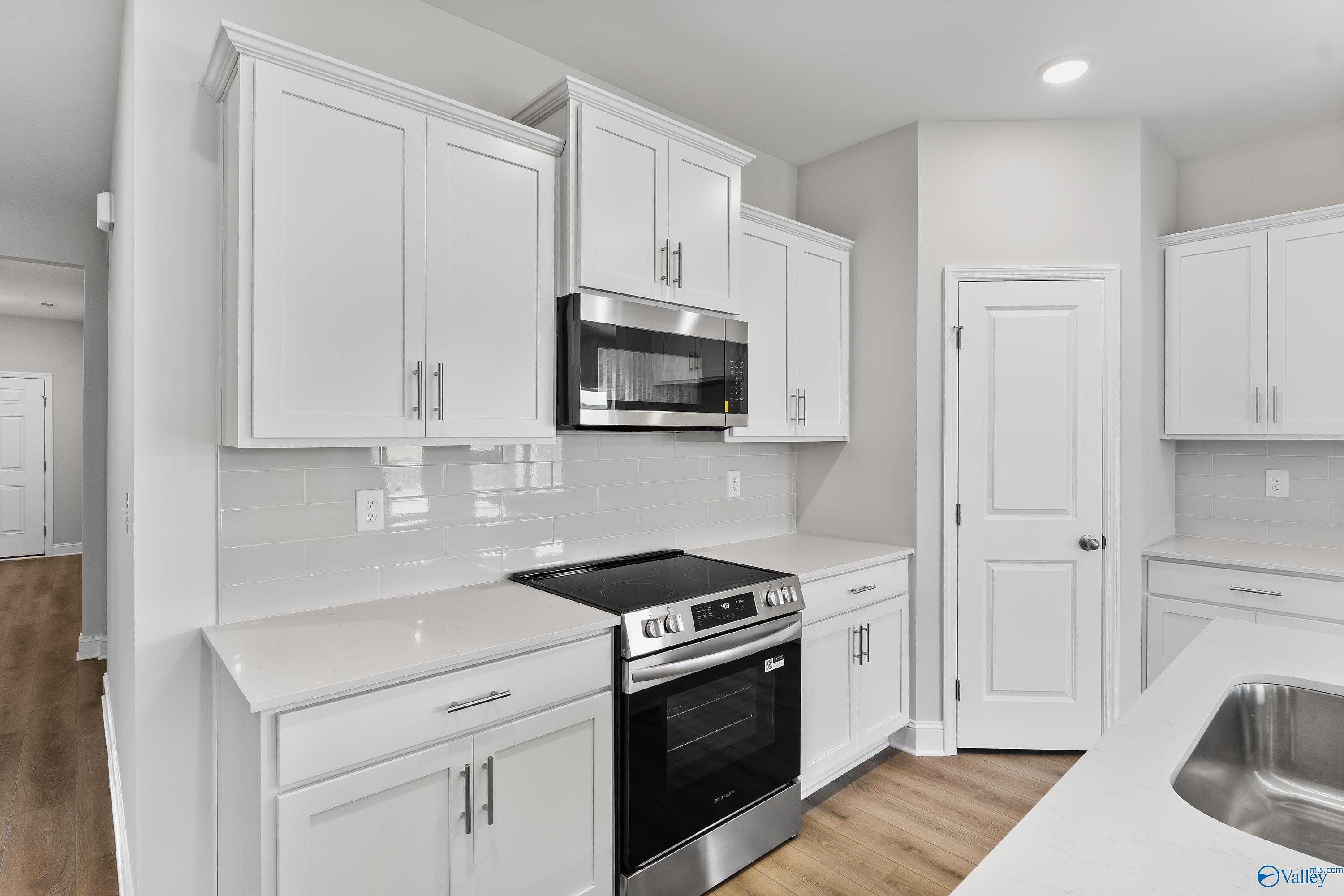 Modern white kitchen with stainless steel appliances, subway tile backsplash in Davidson Homes The Daphne, Hazel Green, Alabama