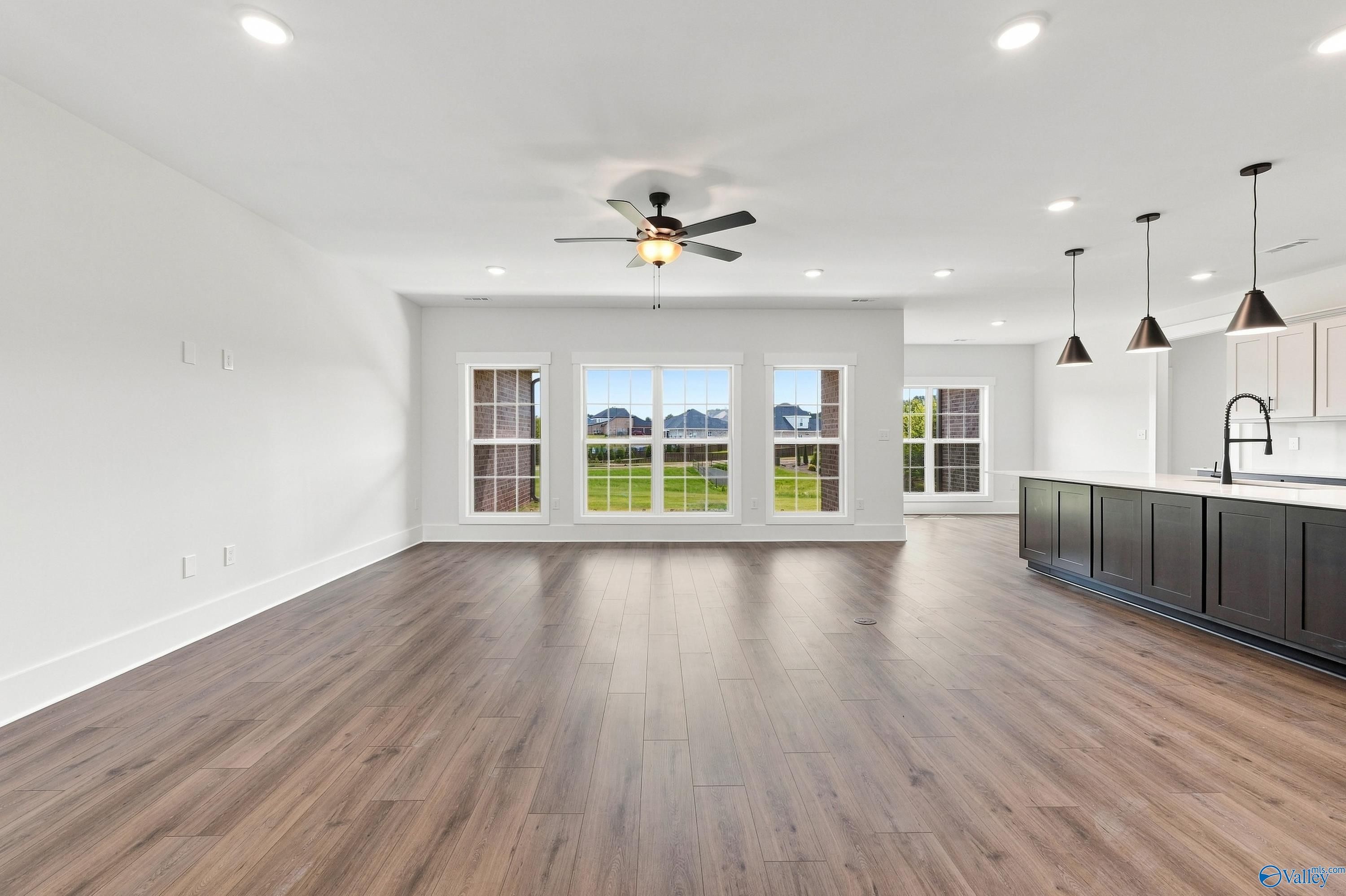 Open-concept living room with hardwood floors and kitchen island in The Valencia floor plan at Riverton Preserve, Huntsville
